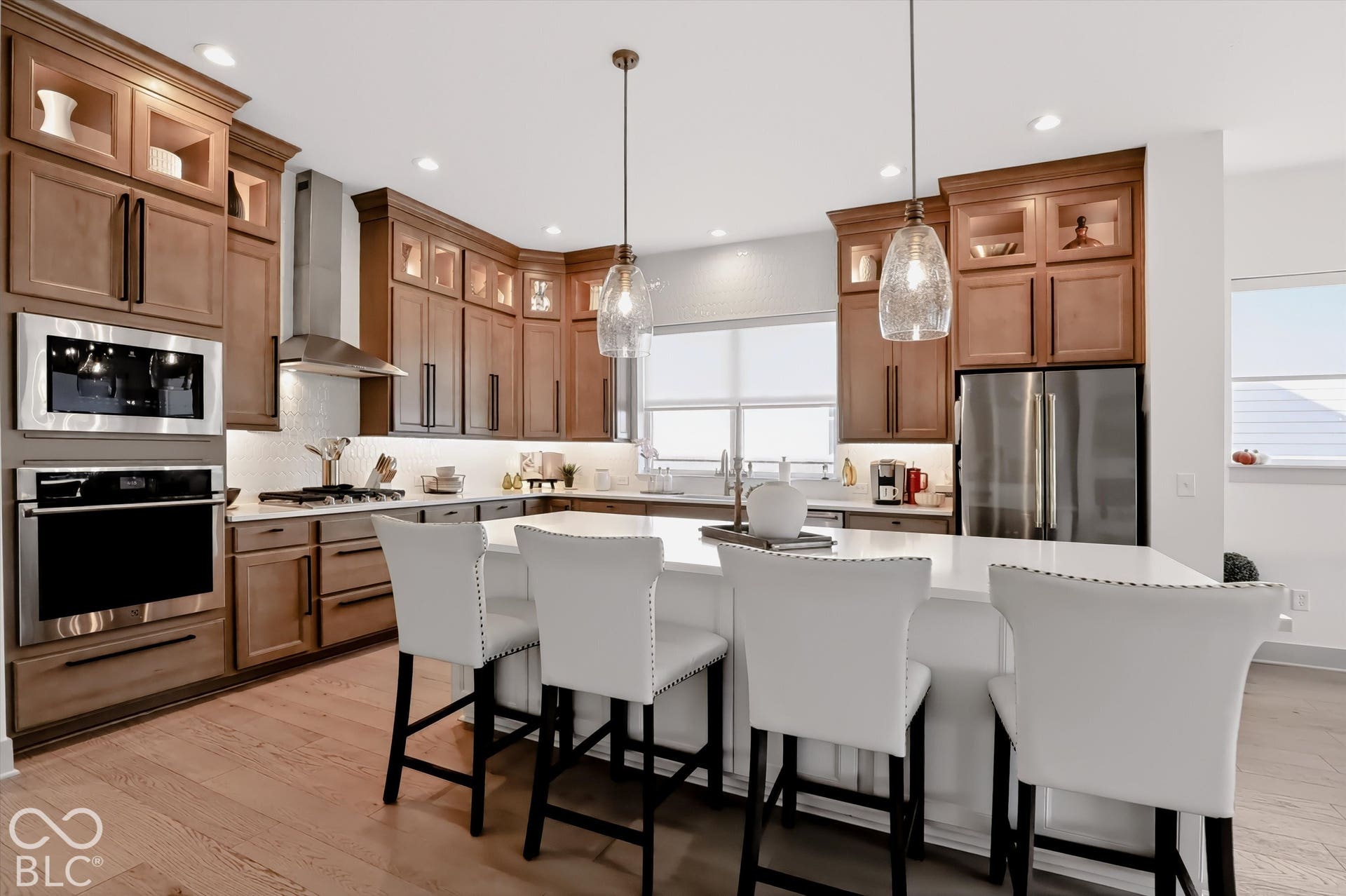 Kitchen featuring wood cabinetry, stone countertops, a large center island, stainless steel wall-mounted oven and microwave, and glass pendant lighting