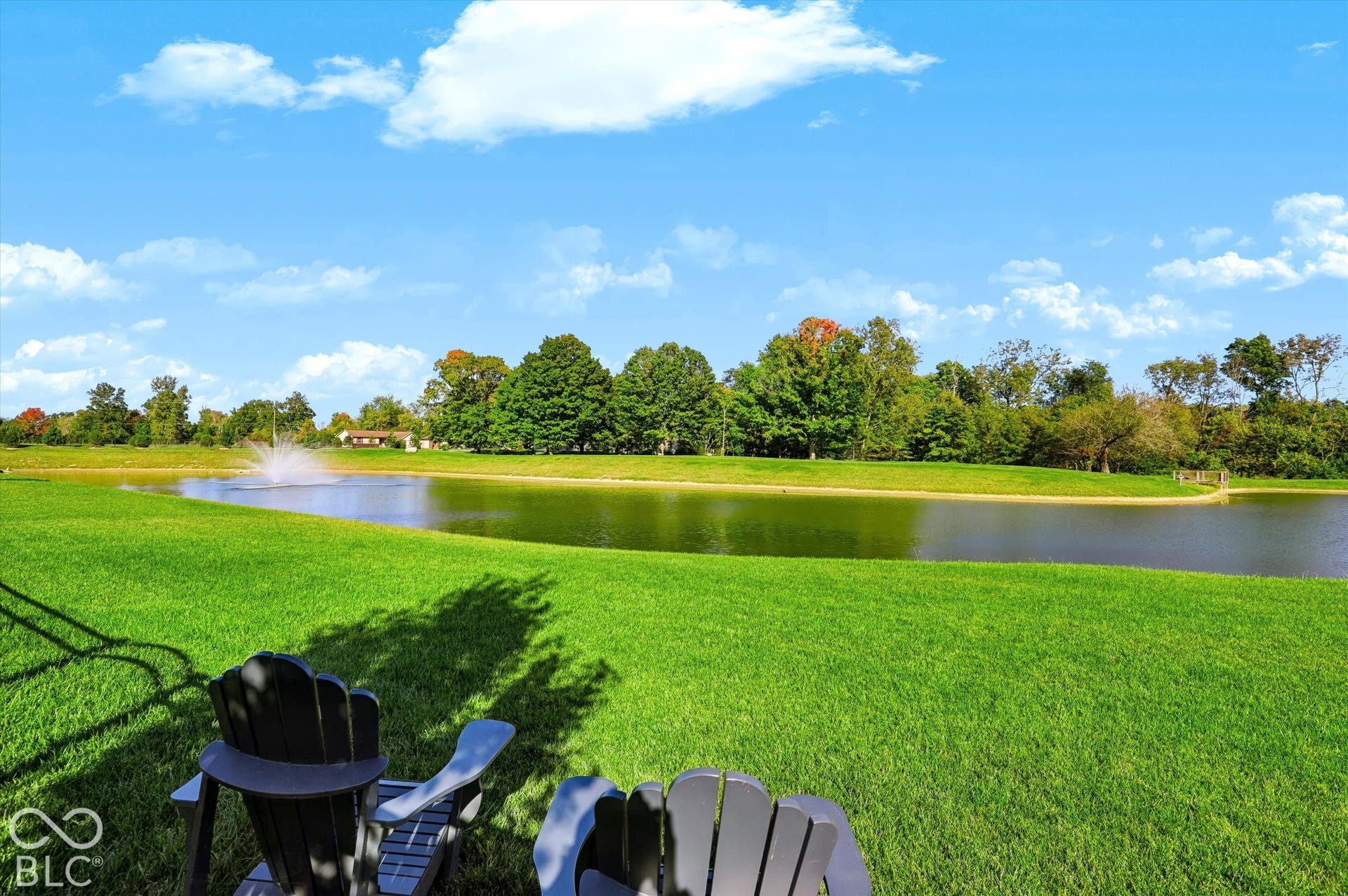 Expansive lawn area featuring a pond with a built-in fountain and mature trees