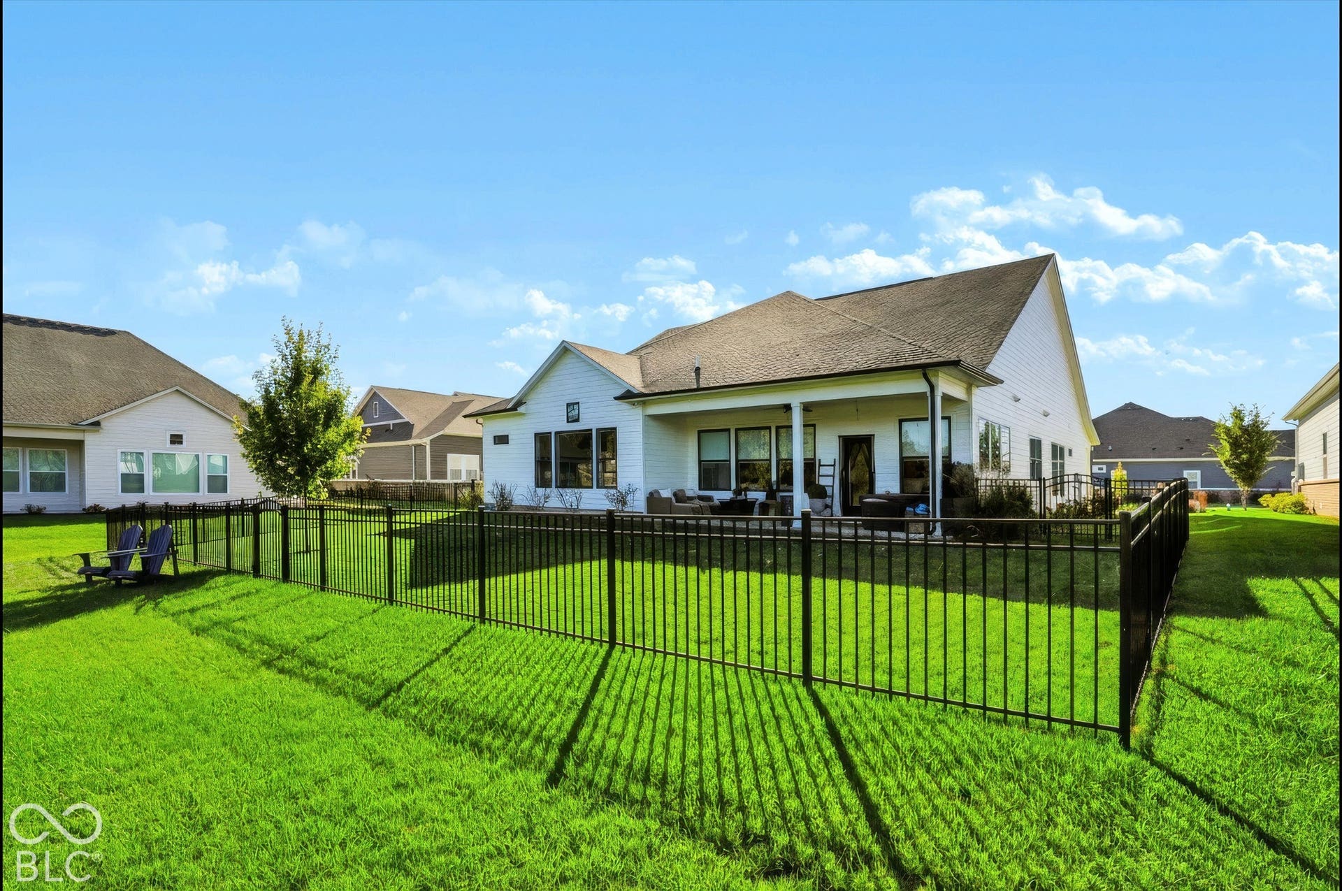 Rear exterior featuring a covered patio, black metal perimeter fencing, and horizontal siding