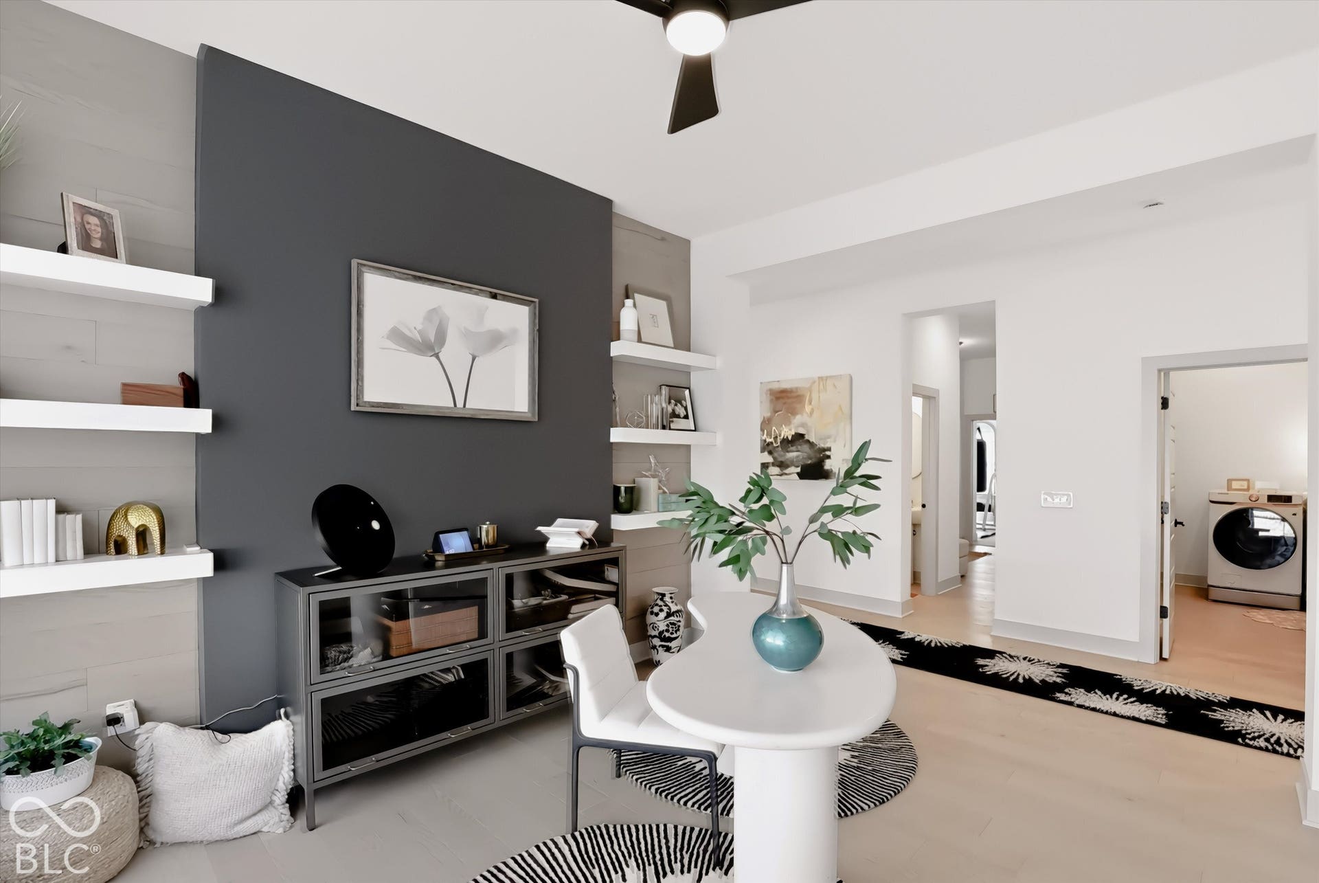 Accent wall with integrated wood-plank detailing, multi-level floating shelving, wood-finish flooring, and a modern ceiling fan