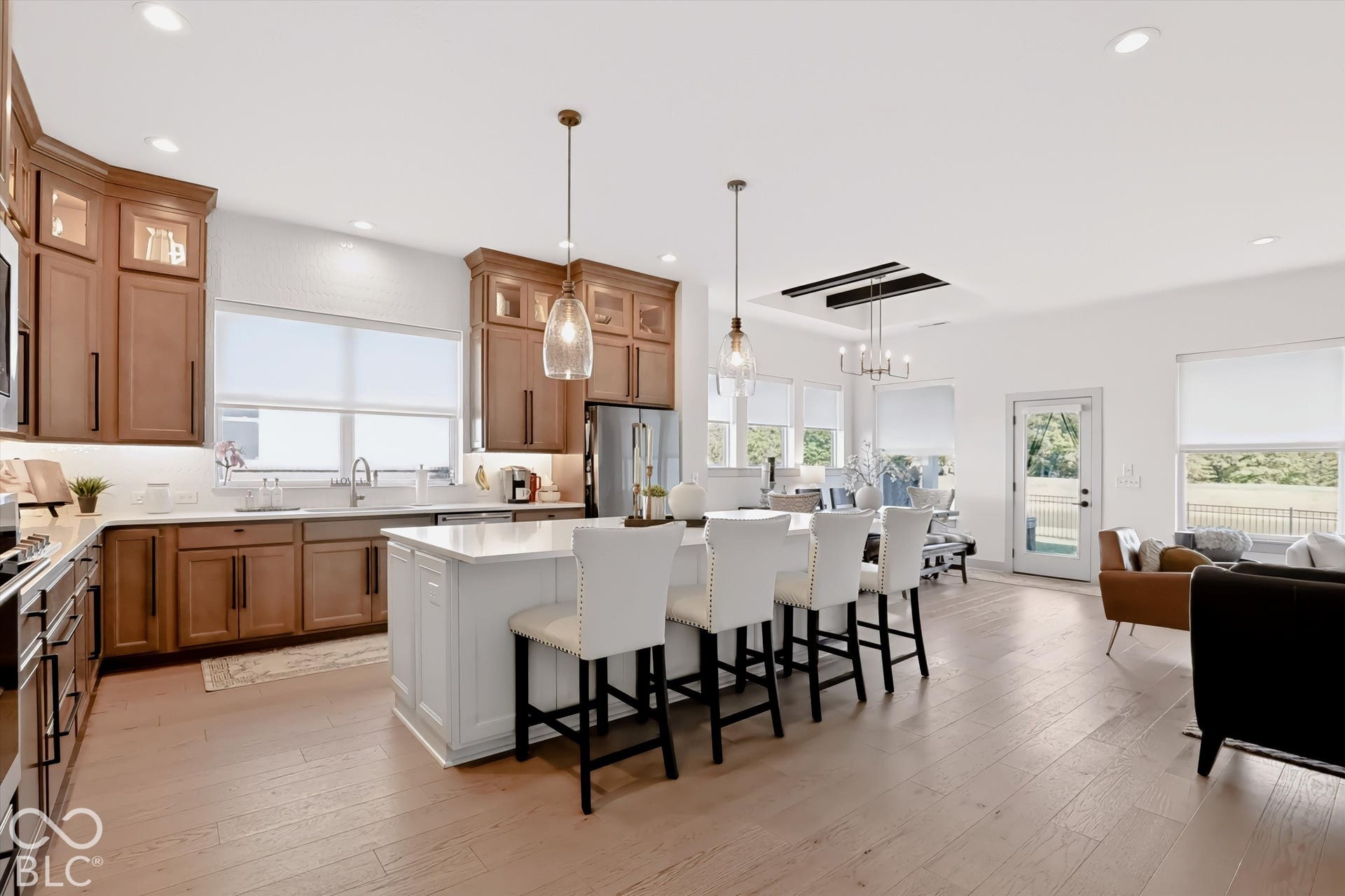 Kitchen featuring wood cabinetry, quartz-topped center island with seating, pendant lighting, recessed lighting, and wood-finish flooring
