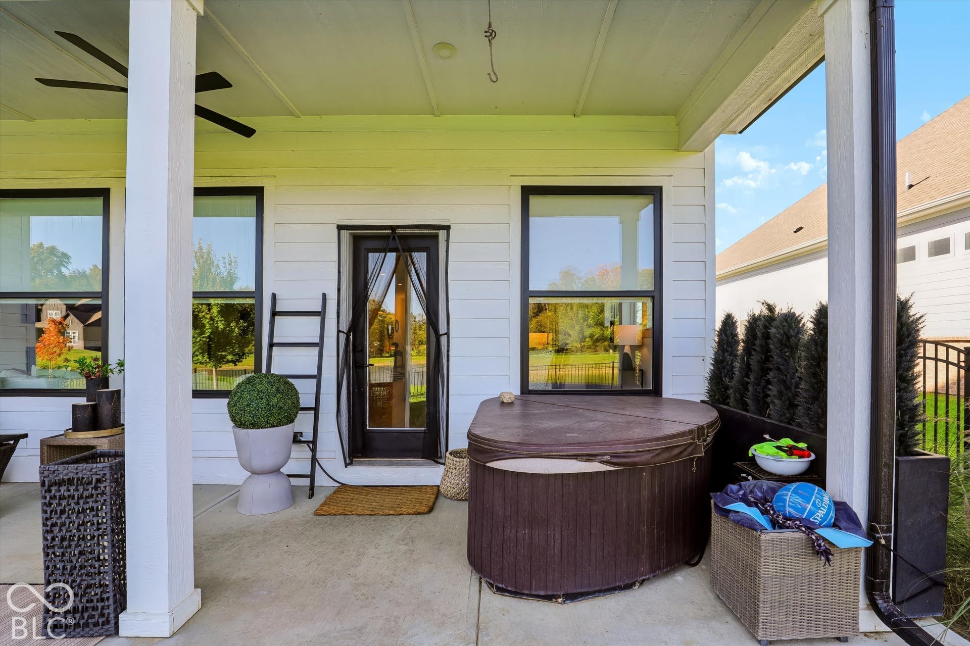 Covered patio featuring a concrete floor, horizontal siding, black-framed windows, and a ceiling-mounted fan