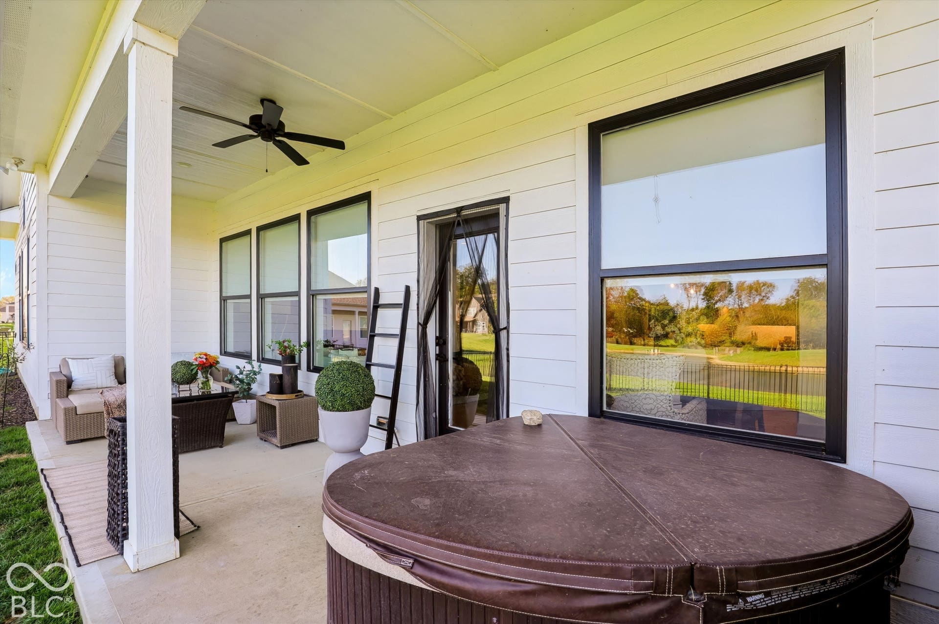 Covered concrete patio featuring horizontal lap siding, a ceiling fan, and black window frames