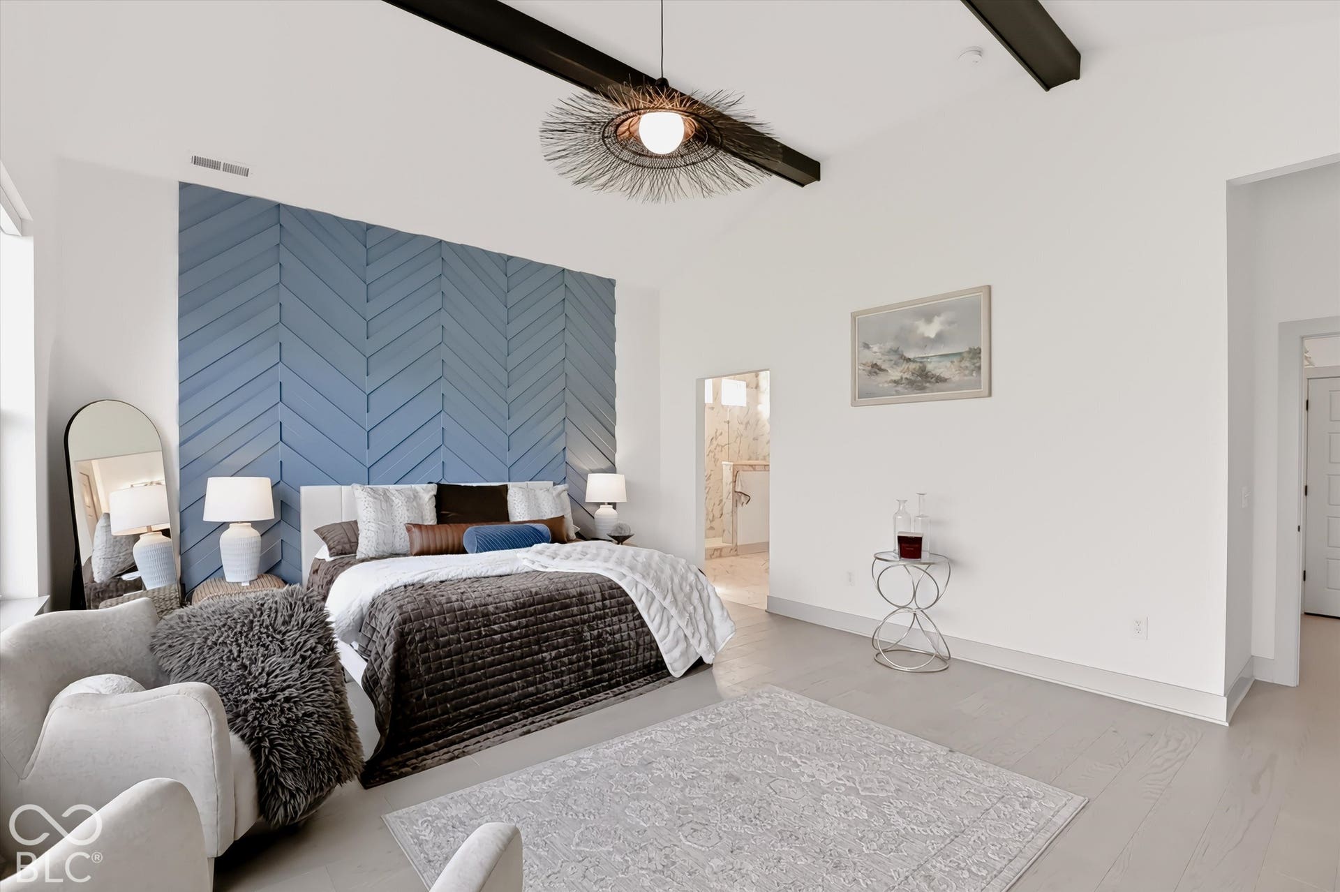 Vaulted ceilings with exposed beams, herringbone-patterned accent wall, and wood-finish flooring