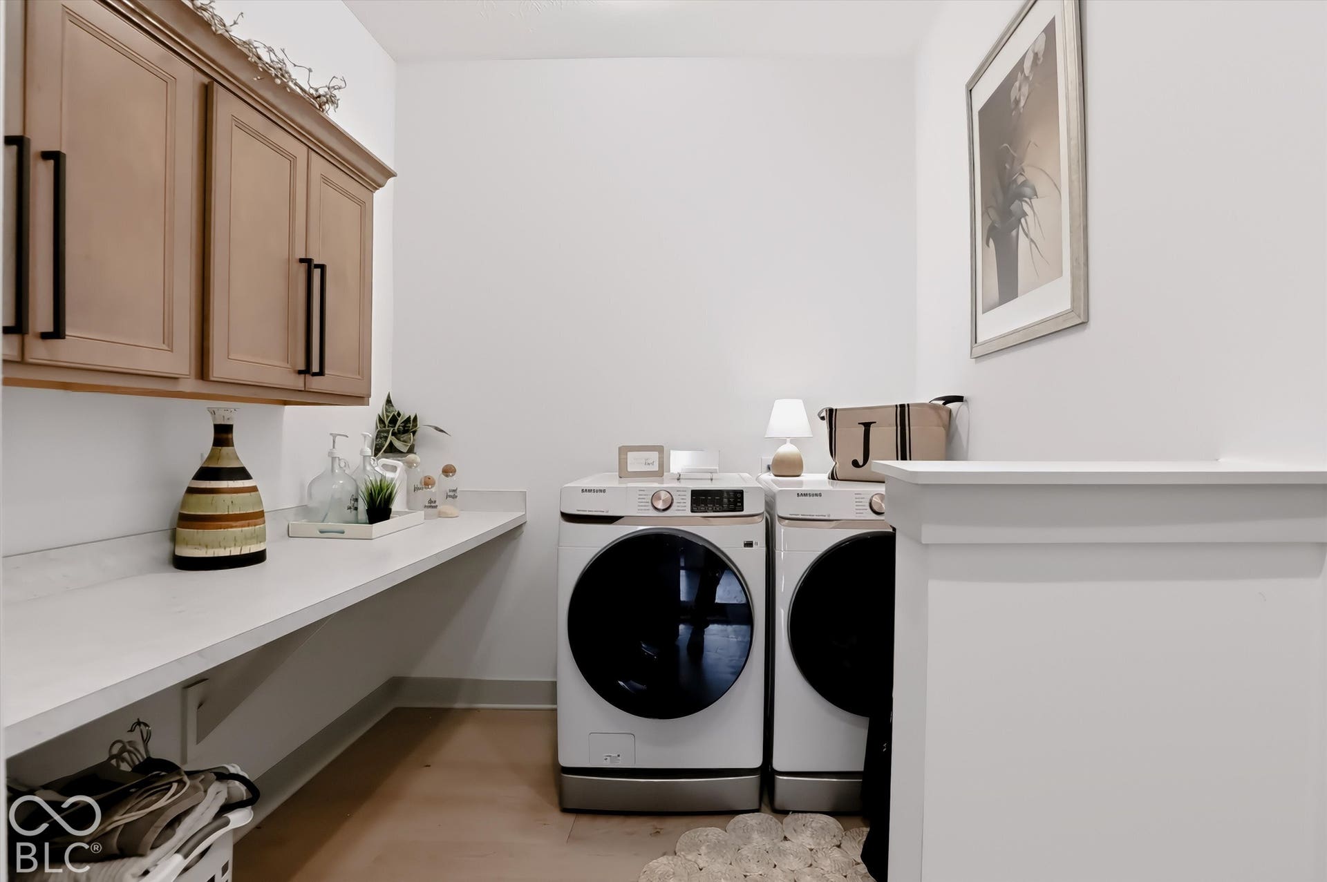 Laundry room featuring wood-finish wall-mounted cabinetry, matte black hardware, and an expansive white countertop