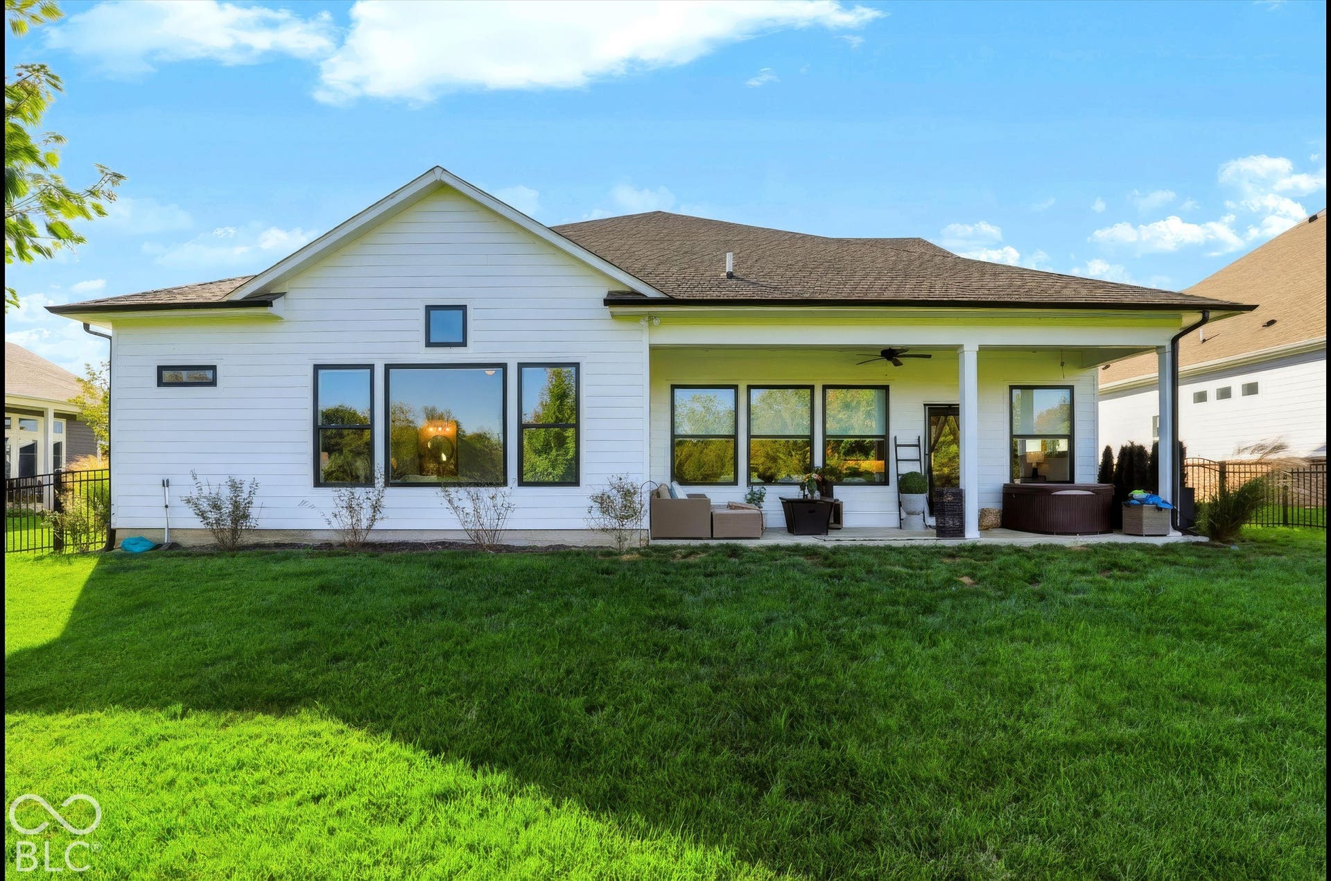 White horizontal siding exterior featuring a covered rear patio, large-format windows with black frames, and a shingle roof