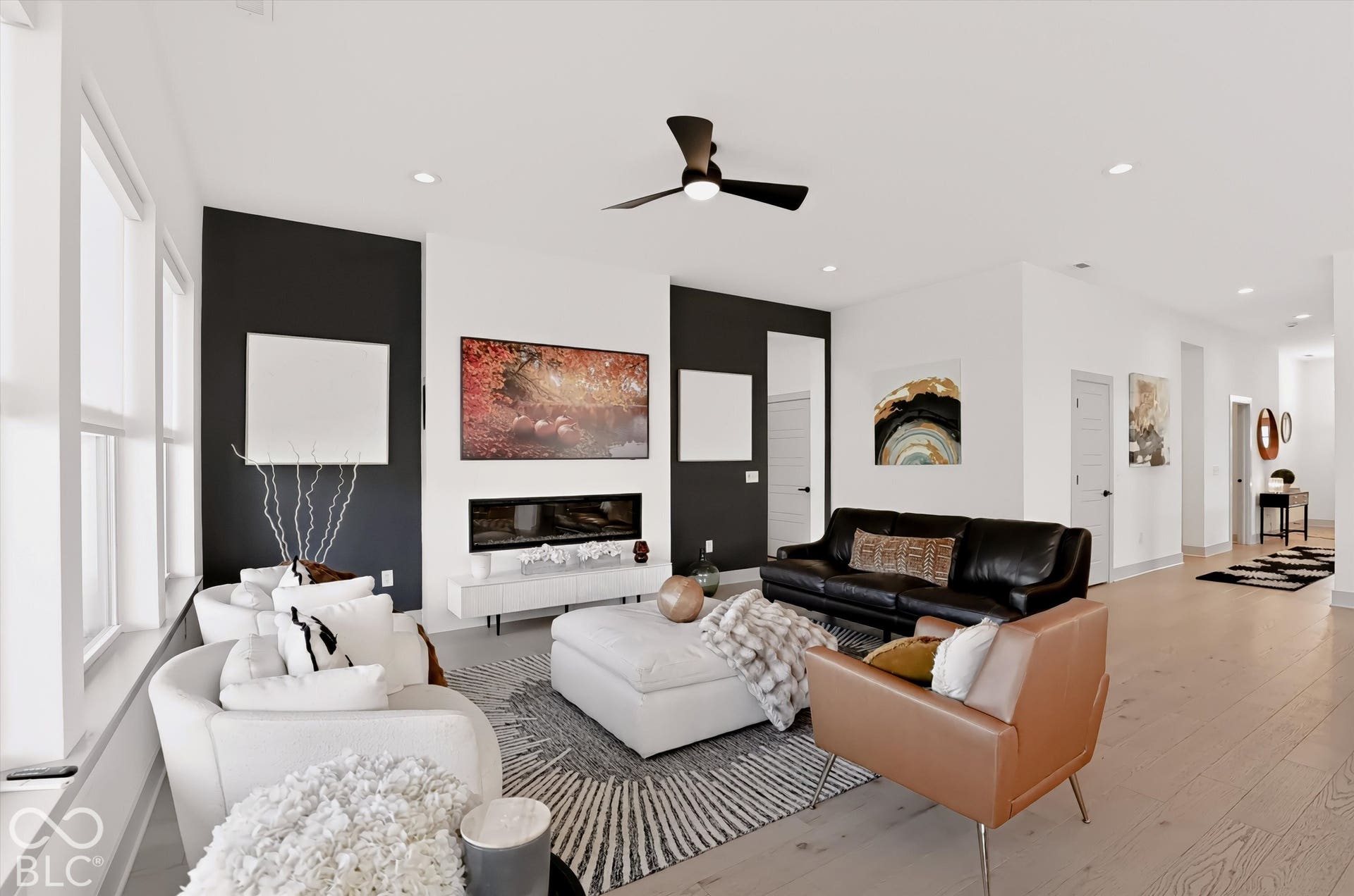 Living area featuring a linear fireplace with a contrasting dark accent wall, recessed lighting, a modern ceiling fan, and light-toned wood-finish flooring
