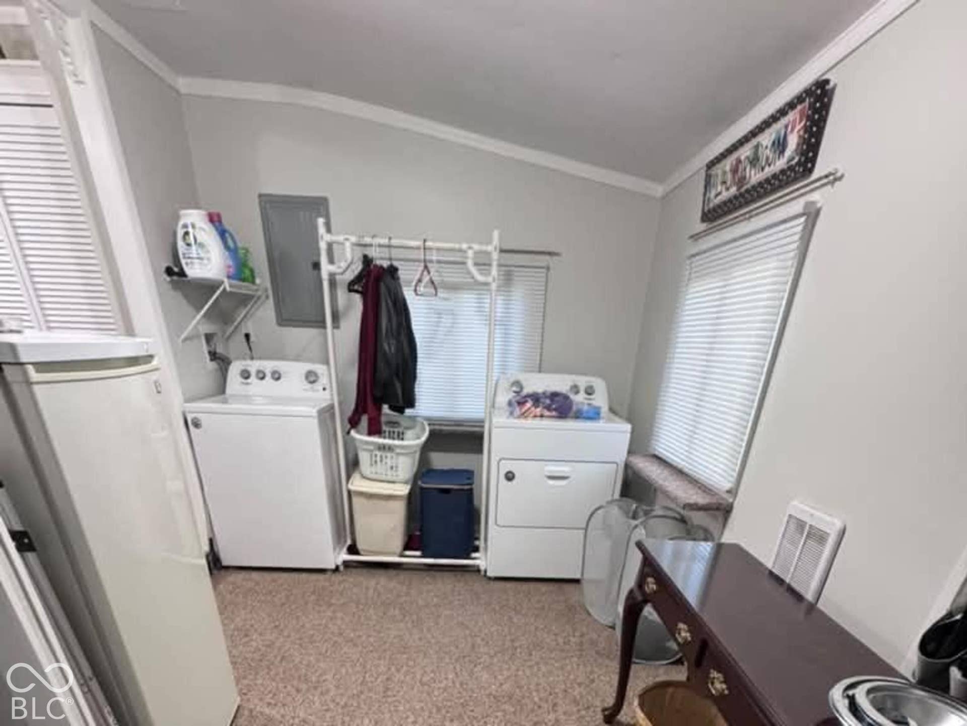 906 S Patterson, Lebanon, IN 46052 Dedicated utility room featuring wall-to-wall carpeting, dual windows with horizontal blinds, and a built-in wire shelving unit