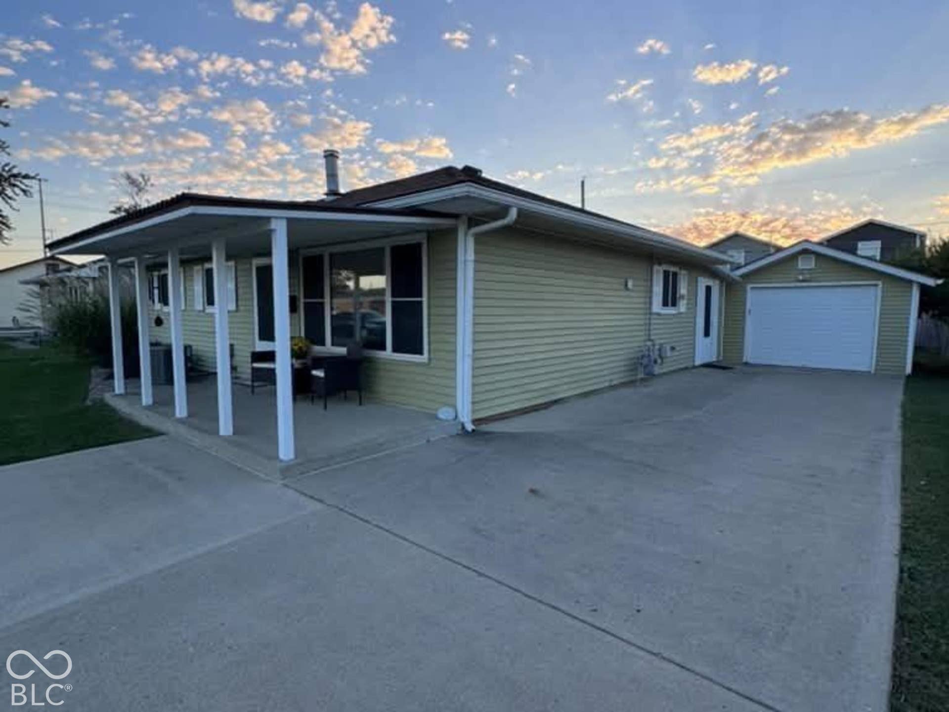906 S Patterson, Lebanon, IN 46052 Exterior featuring light-toned horizontal siding, a covered front porch with support pillars, a concrete driveway, and a detached one-car garage