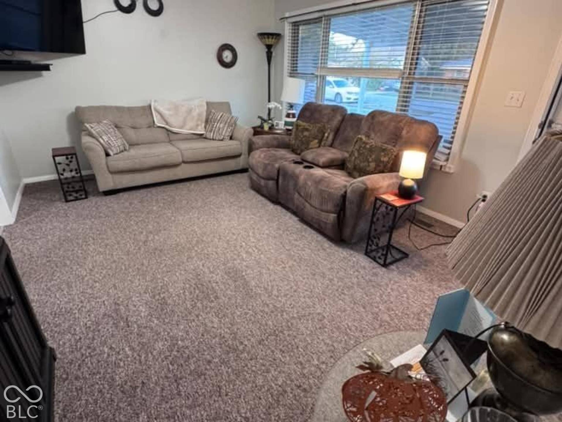 906 S Patterson, Lebanon, IN 46052 Neutral-toned interior space featuring wall-to-wall carpeting, a multi-blade ceiling fan with integrated lighting, and a large multi-pane window with horizontal blinds