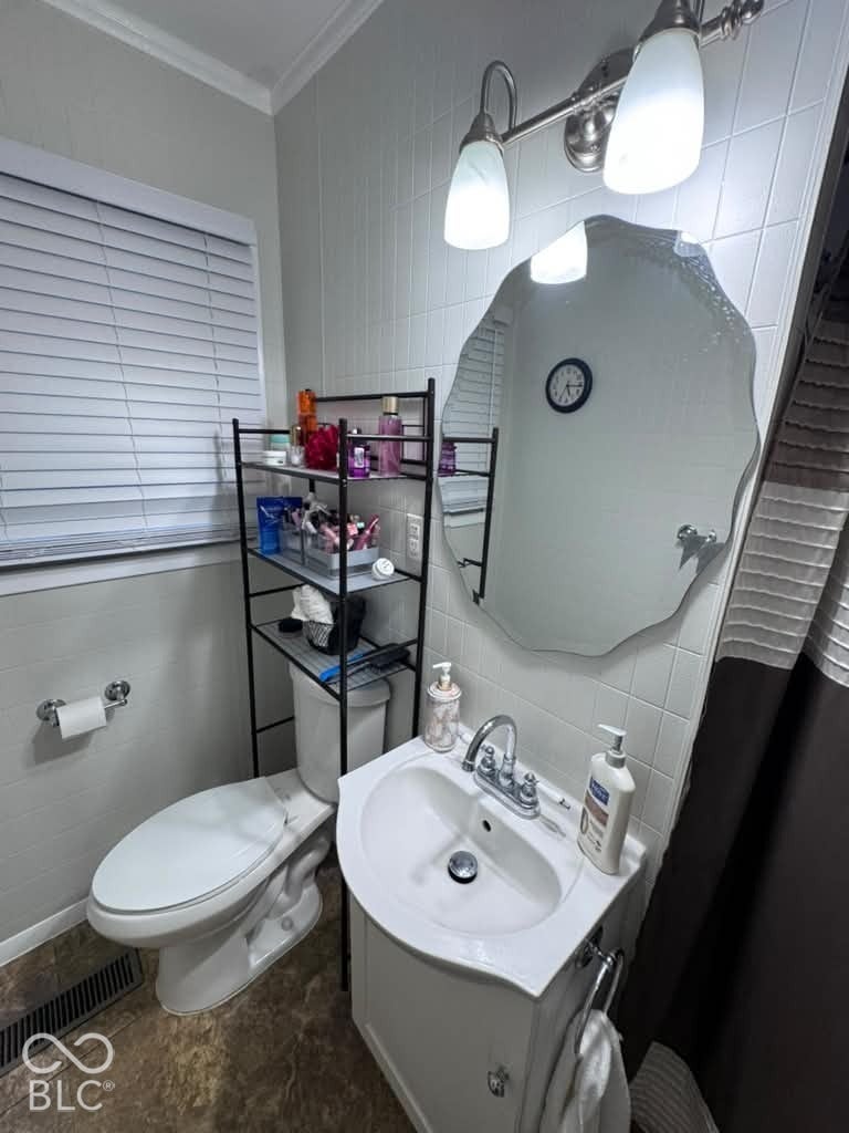 906 S Patterson, Lebanon, IN 46052 Pedestal sink with chrome faucet, scalloped wall mirror, two-light fixture with glass shades, tile wall backsplash, and horizontal window blinds