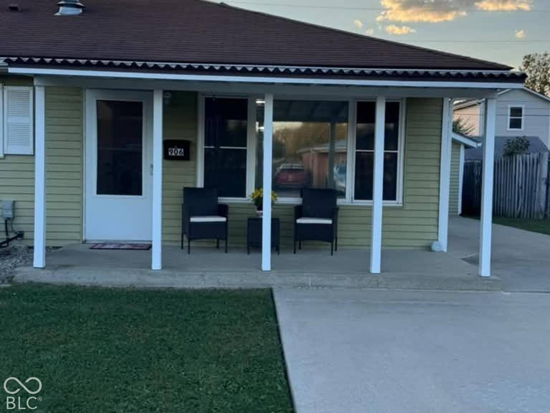 906 S Patterson, Lebanon, IN 46052 Exterior featuring horizontal siding, a covered front porch with support pillars, a concrete driveway, and a chimney