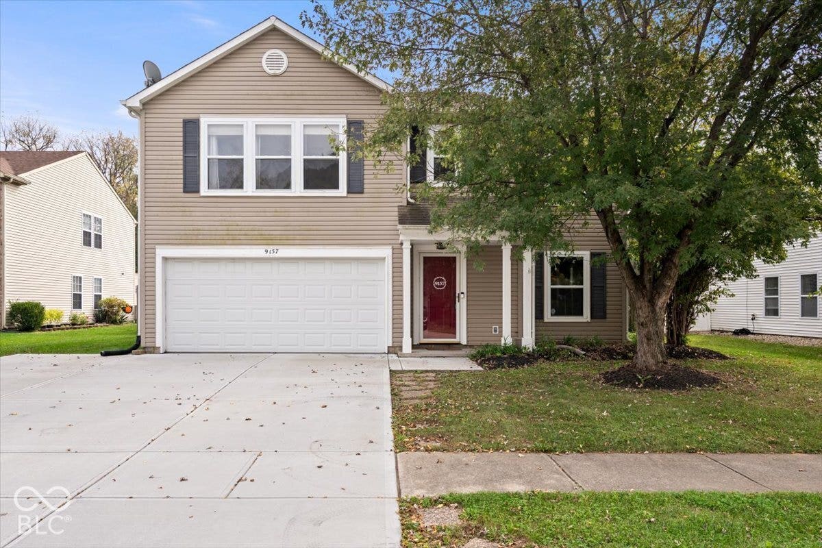 Two-story residence featuring horizontal lap siding, an attached two-car garage, a covered front entryway with columns, and dark-toned shutter accents