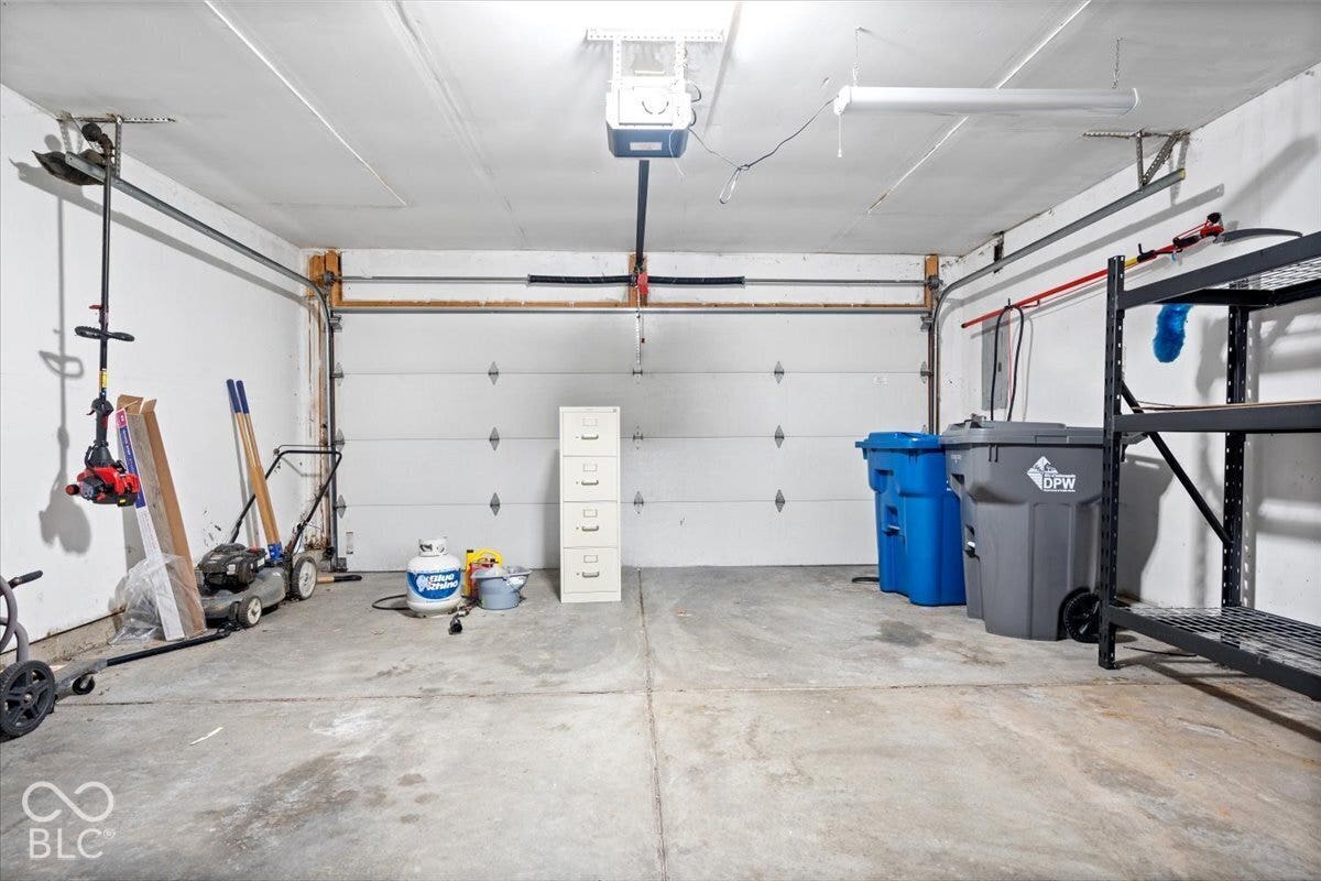 Attached multi-car garage featuring a concrete floor, motorized sectional garage door, and ceiling-mounted electrical lighting