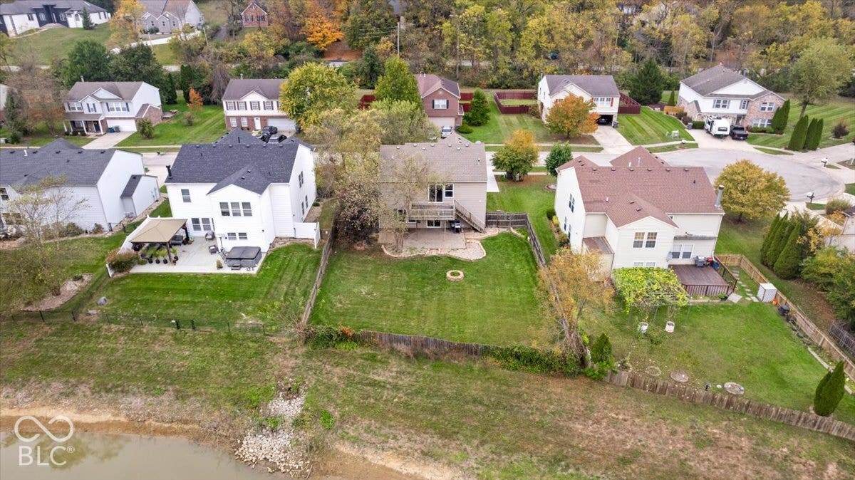 Aerial perspective of residential properties featuring fenced yards, paved patios, elevated wooden decks, and water frontage