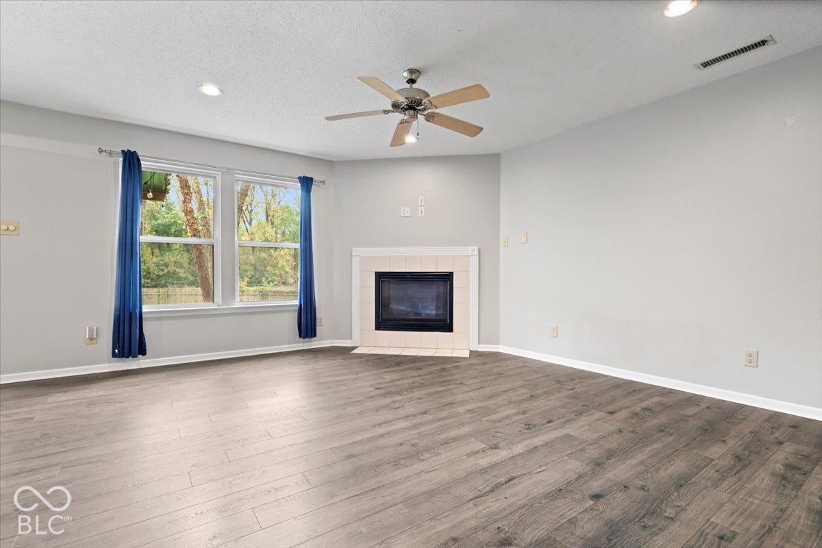 Wood-finish flooring, fireplace with a tile surround, ceiling fan, and recessed lighting