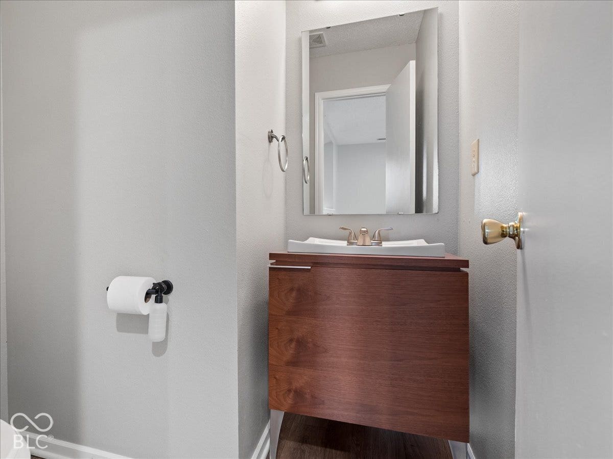 Wall-mounted vanity featuring a wood-finish cabinet, rectangular vessel sink, polished metal faucet, and wall-mounted mirror