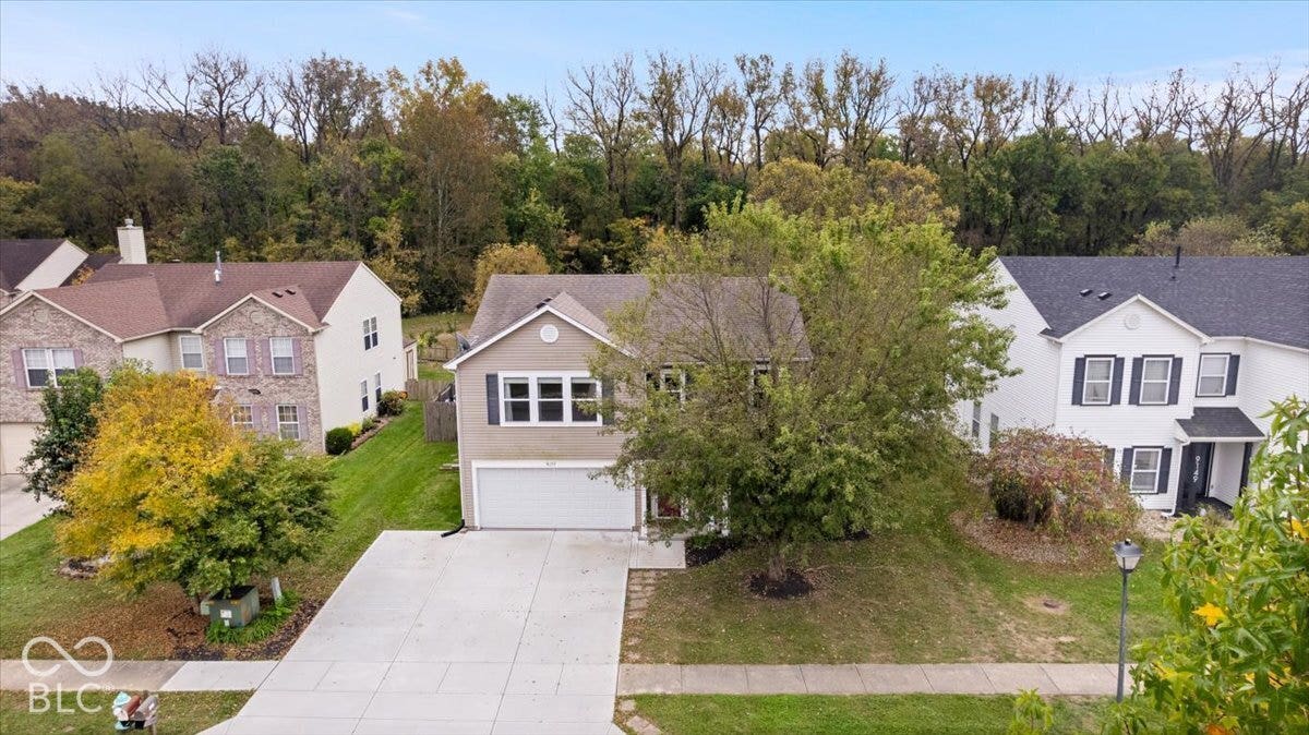 Two-story suburban residence featuring a neutral-toned facade, decorative window shutters, a front-facing attached two-car garage, and a concrete driveway