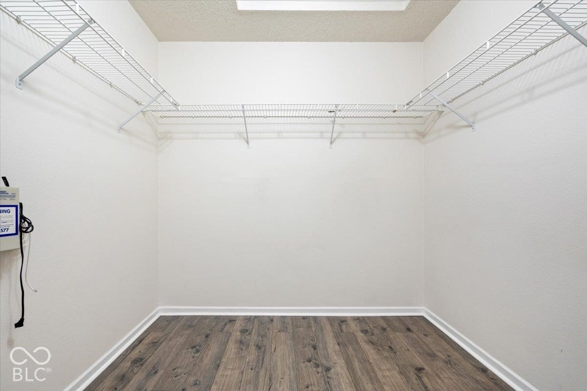 Storage area featuring wood-finish flooring and multi-tiered white wire shelving