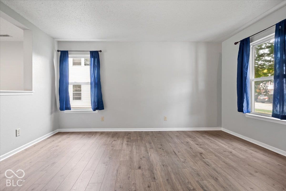 Interior space featuring wood-finish flooring, neutral wall tones, and two windows providing natural illumination
