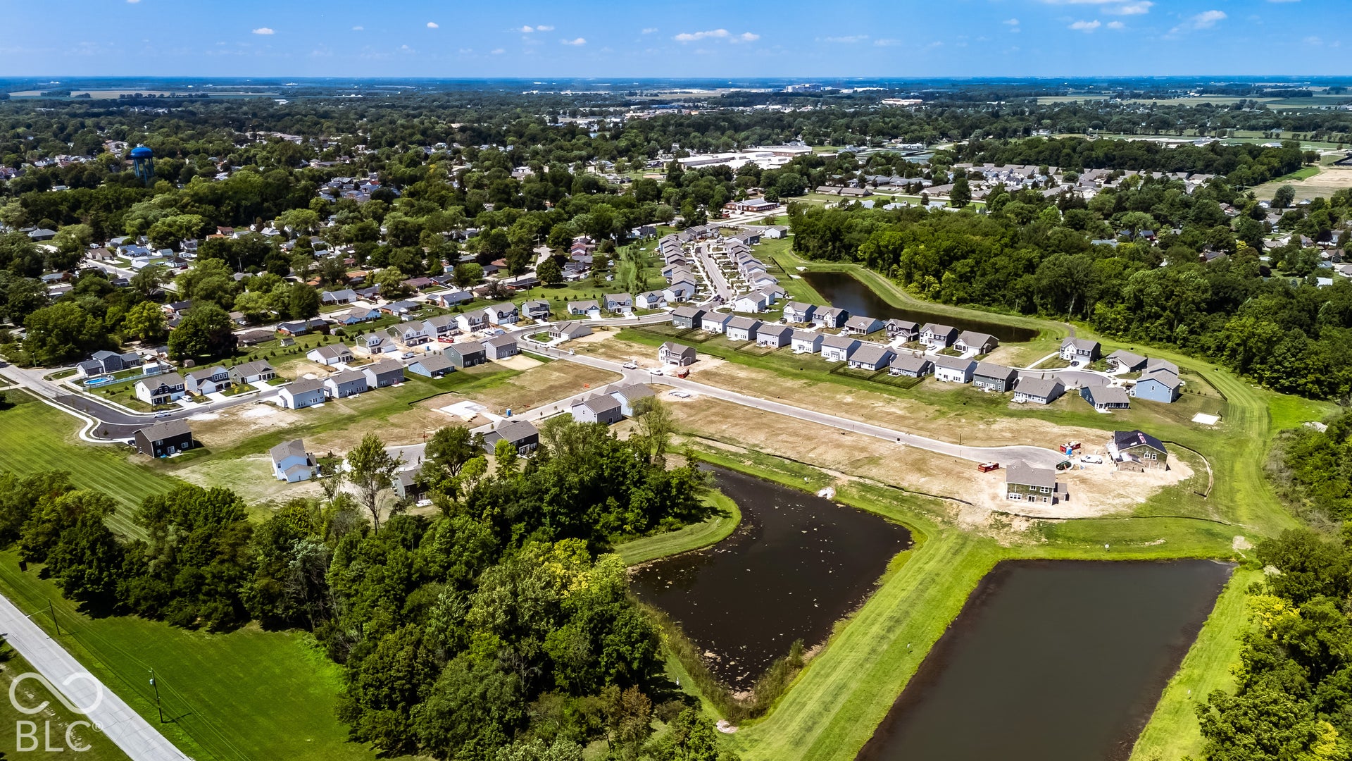 Aerial view of the residential development featuring paved street infrastructure and multiple retention ponds surrounded by mature tree lines