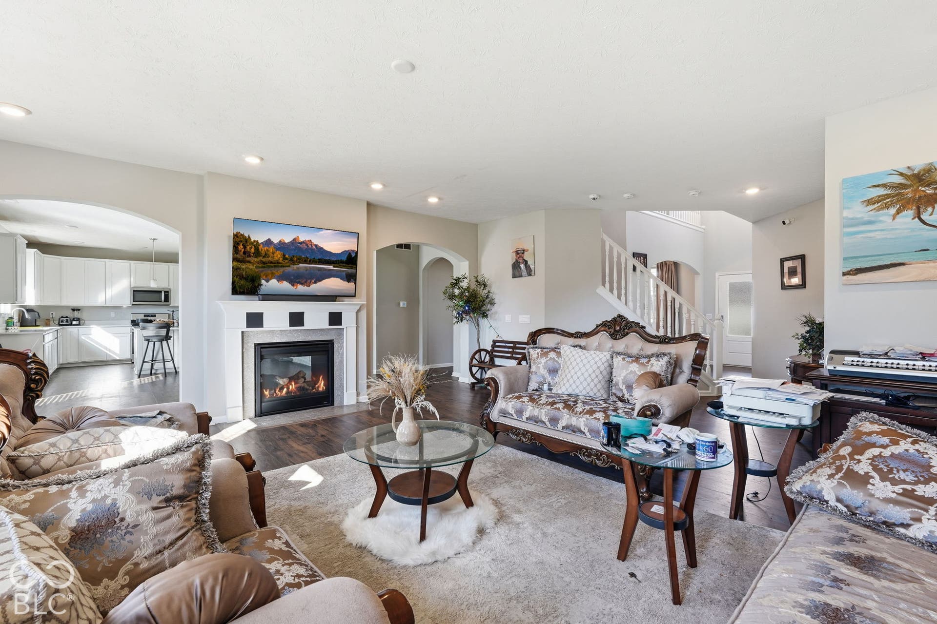 Double-sided gas fireplace in living room with archways leading to the kitchen.