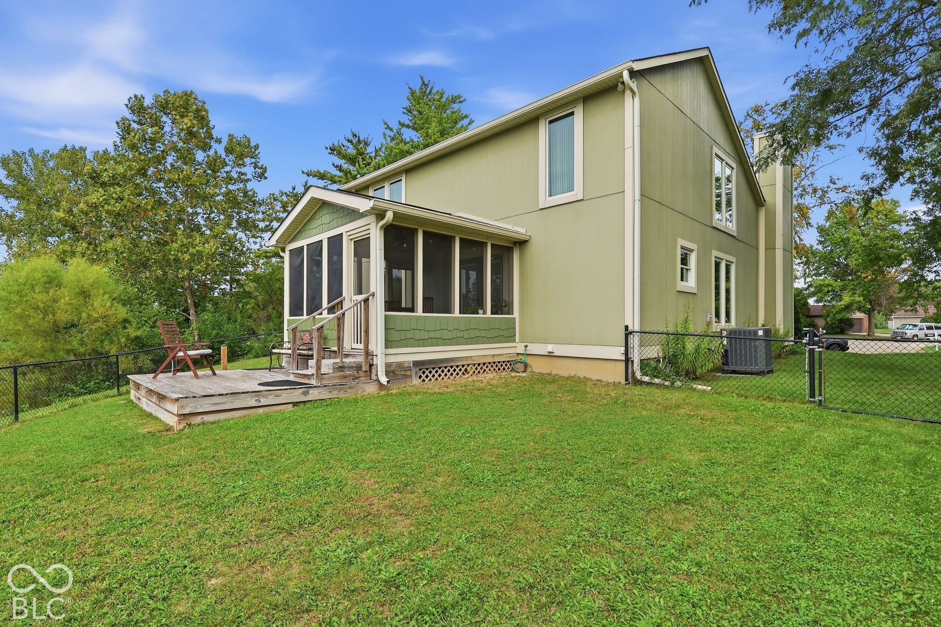 Two-story exterior with vertical siding, screened-in porch with wood decking, and a fenced backyard