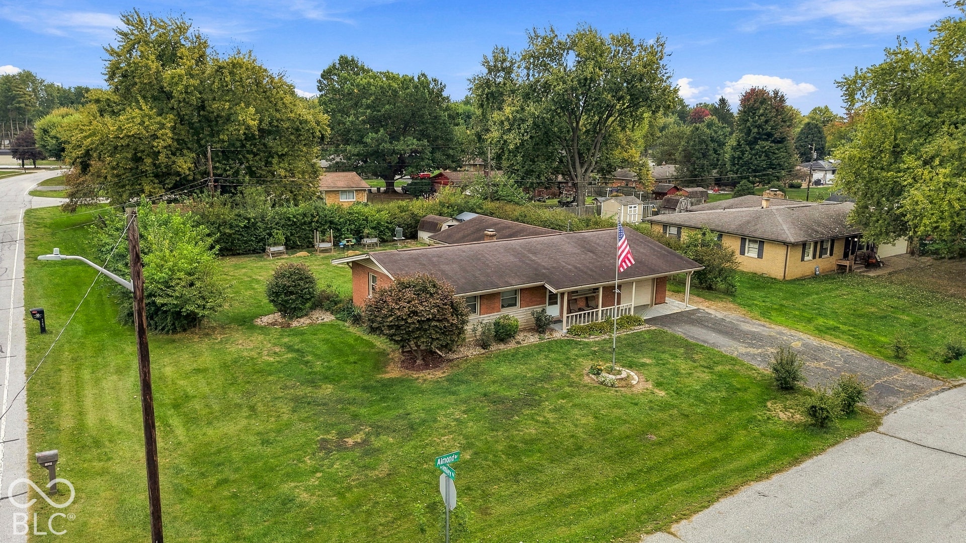 Ranch-style residence featuring a brick and siding exterior, an attached carport, and a paved driveway situated on a spacious corner lot with mature landscaping