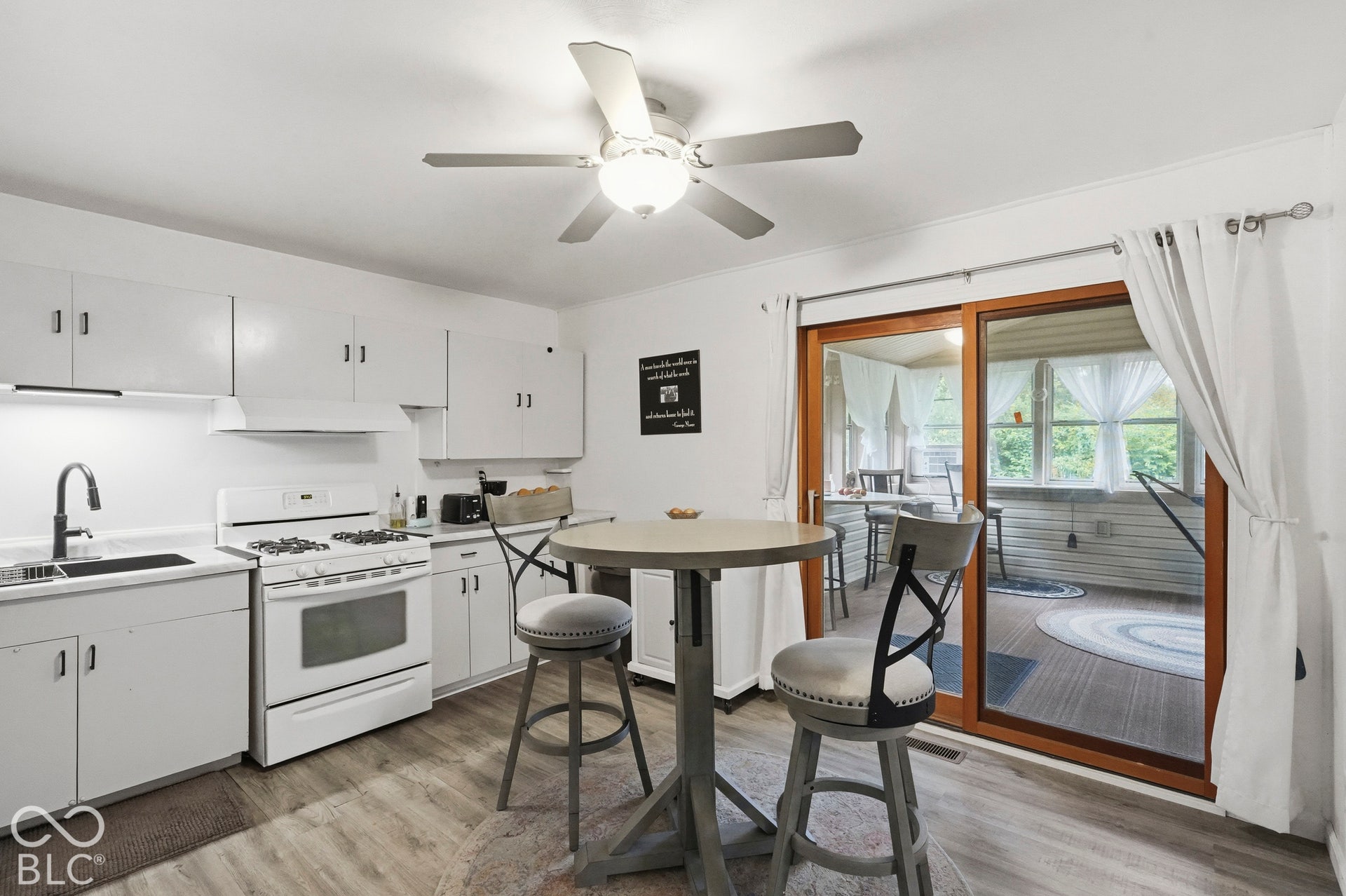 Another view of the kitchen. It has a nice ceiling fan, vinyl plank floors, a nice sliding glass door leading to the spacious sun room.