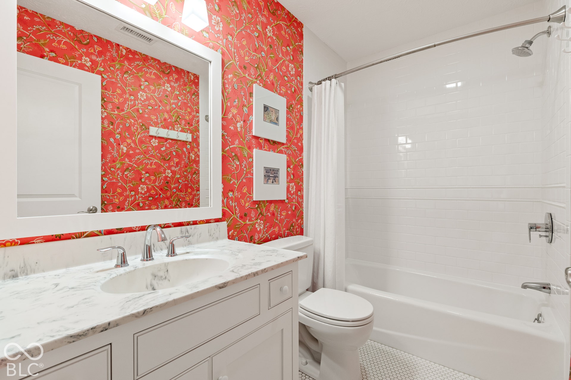 Bathroom featuring a stone-top vanity with an integrated oval sink, white shaker-style cabinetry, a white subway-tile tub surround, and a classic hexagonal floor tile