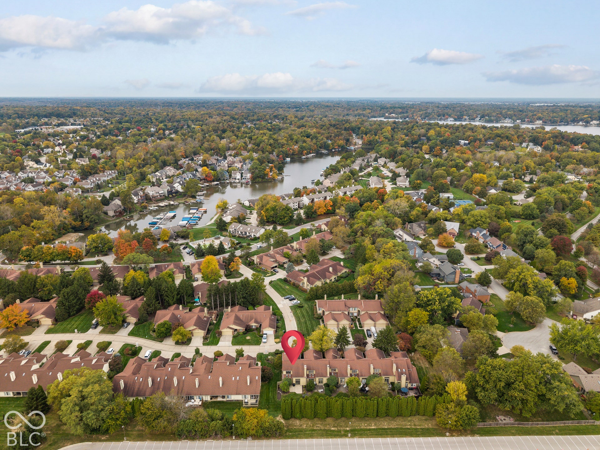 Aerial perspective of a multi-unit property featuring a shingled roof, attached garages, paved driveways, and landscaped green space