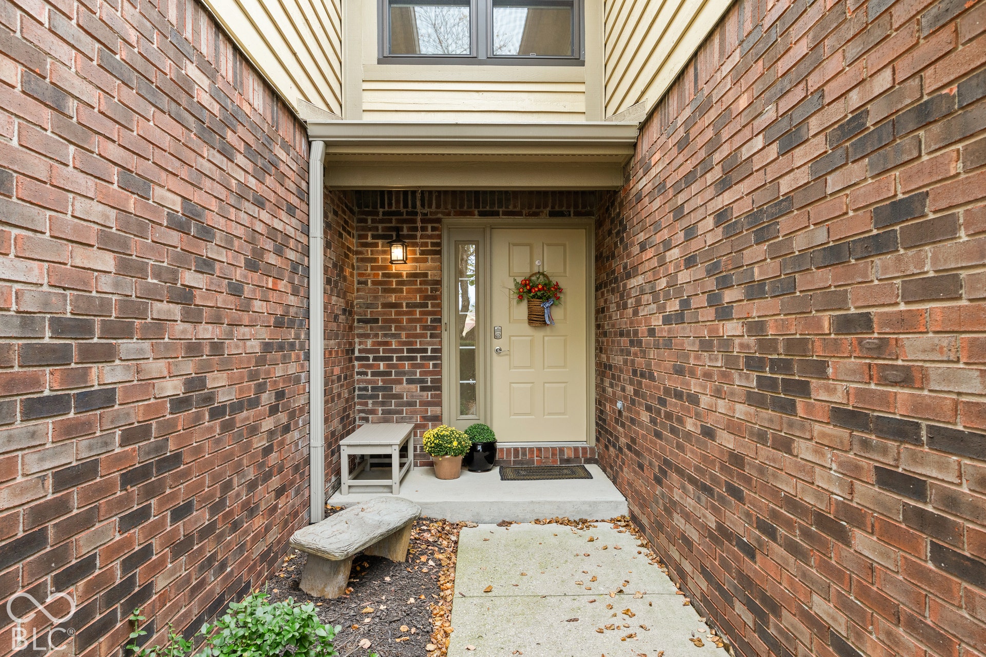 Exterior entryway featuring a red brick facade, recessed porch, six-panel door with sidelight, and concrete walkway