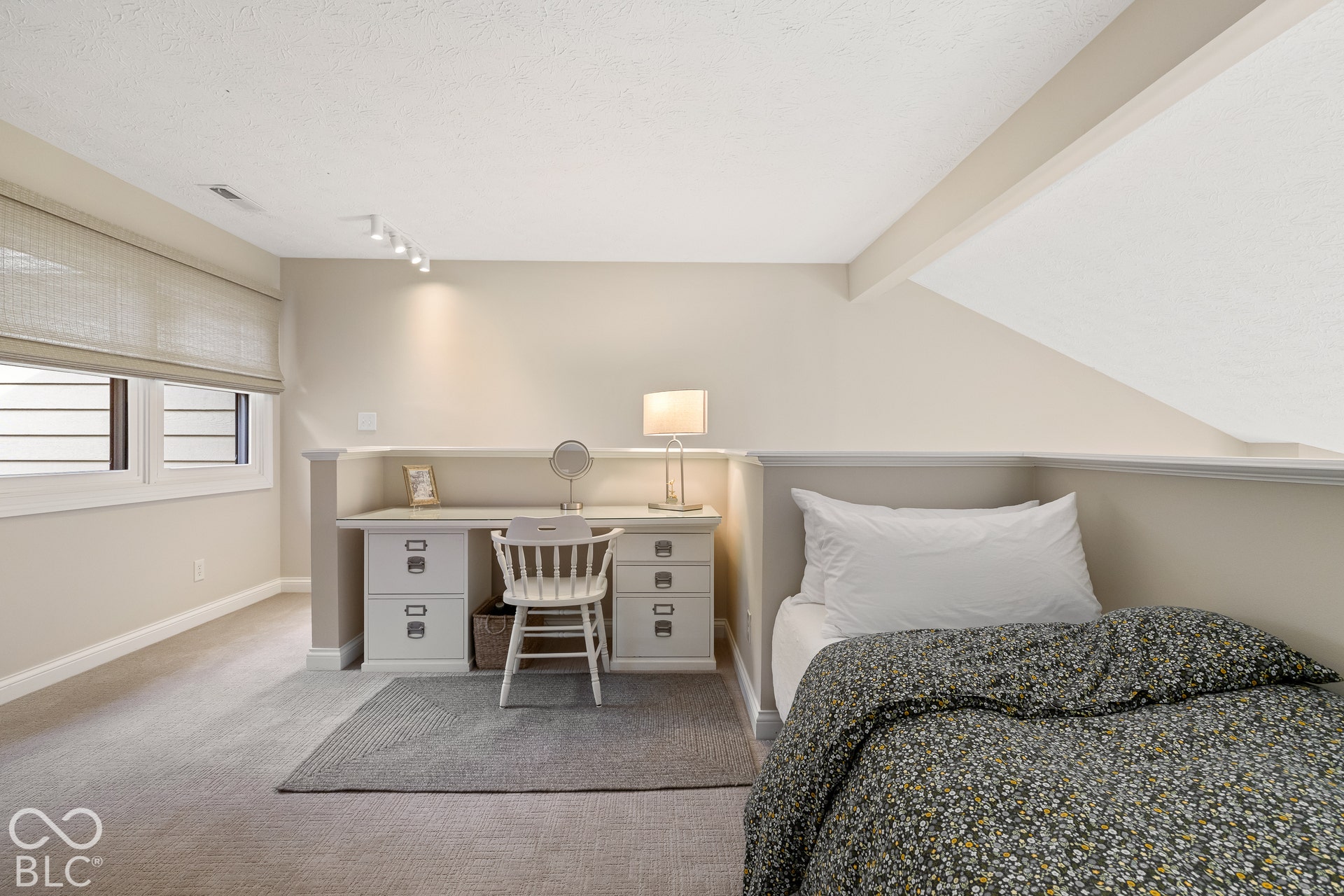 Built-in desk with integrated cabinetry, vaulted ceiling, neutral wall-to-wall carpeting, and track lighting