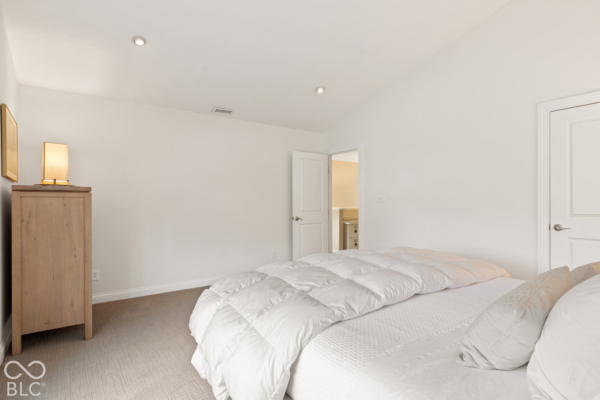 Vaulted ceilings, recessed lighting, and neutral carpeting
