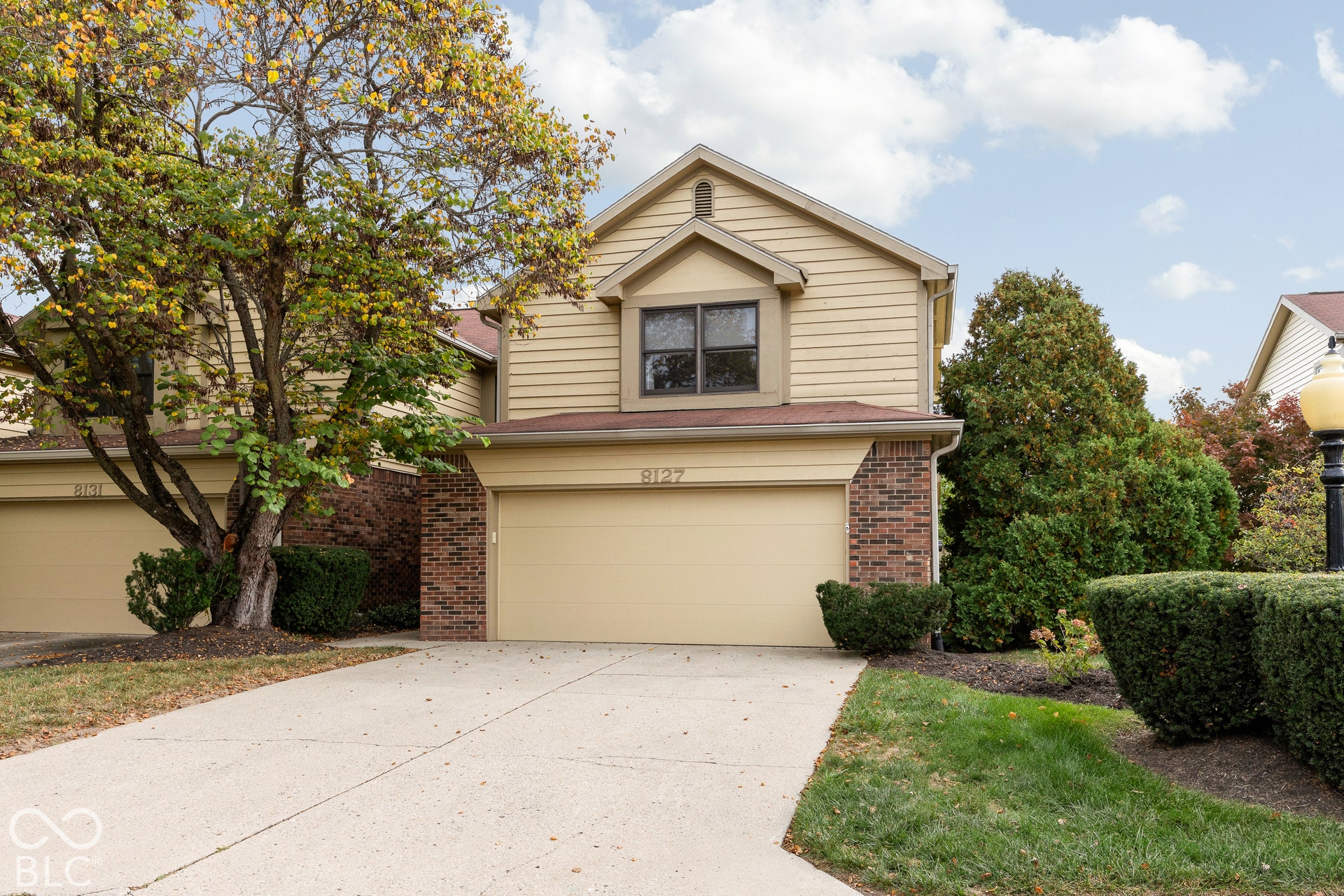 Two-story exterior featuring horizontal lap siding, brick masonry detailing, an attached two-car garage, and concrete driveway