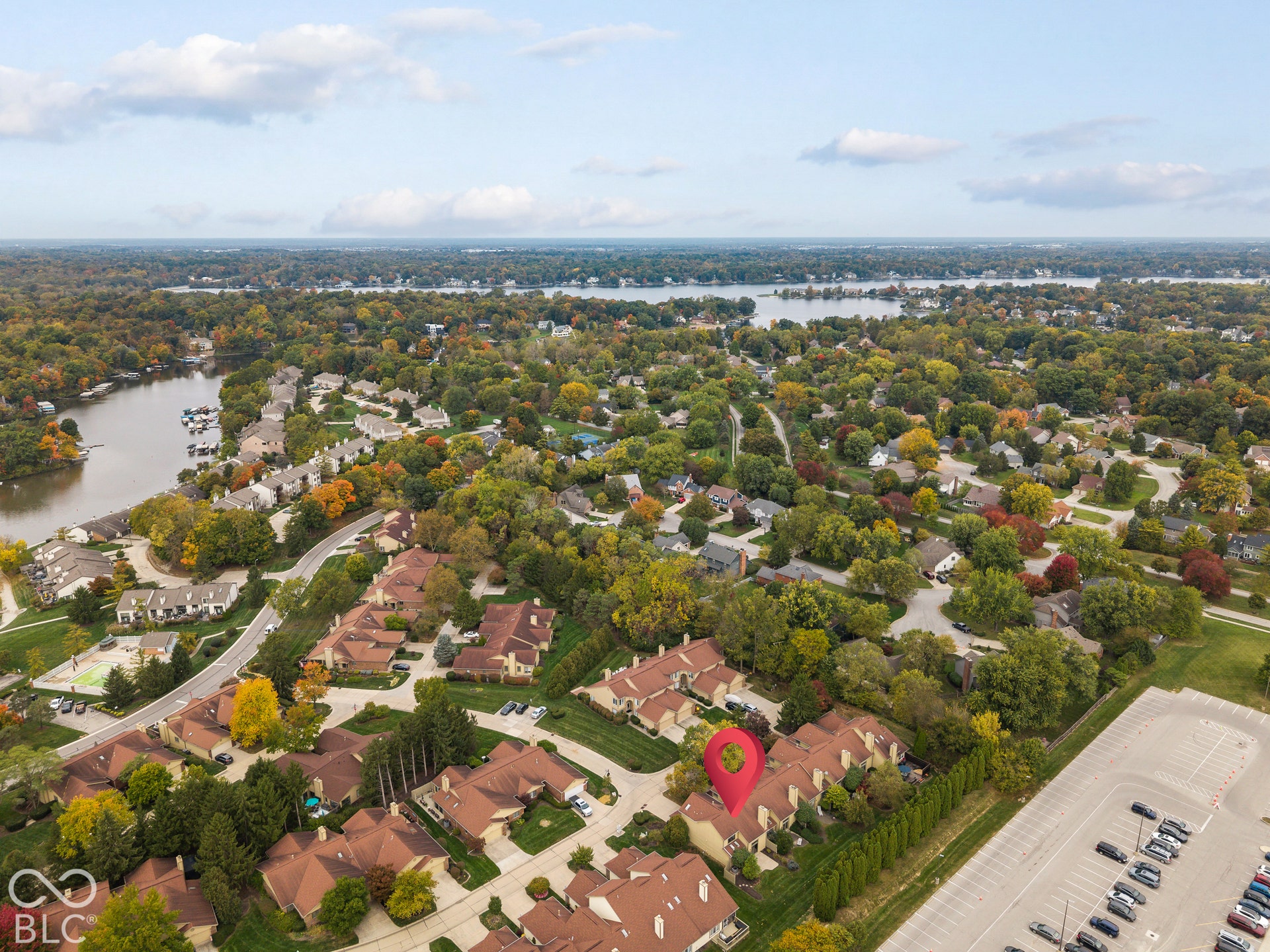 Aerial perspective showcasing a residential community with multi-family structures, mature landscape, and surrounding water features