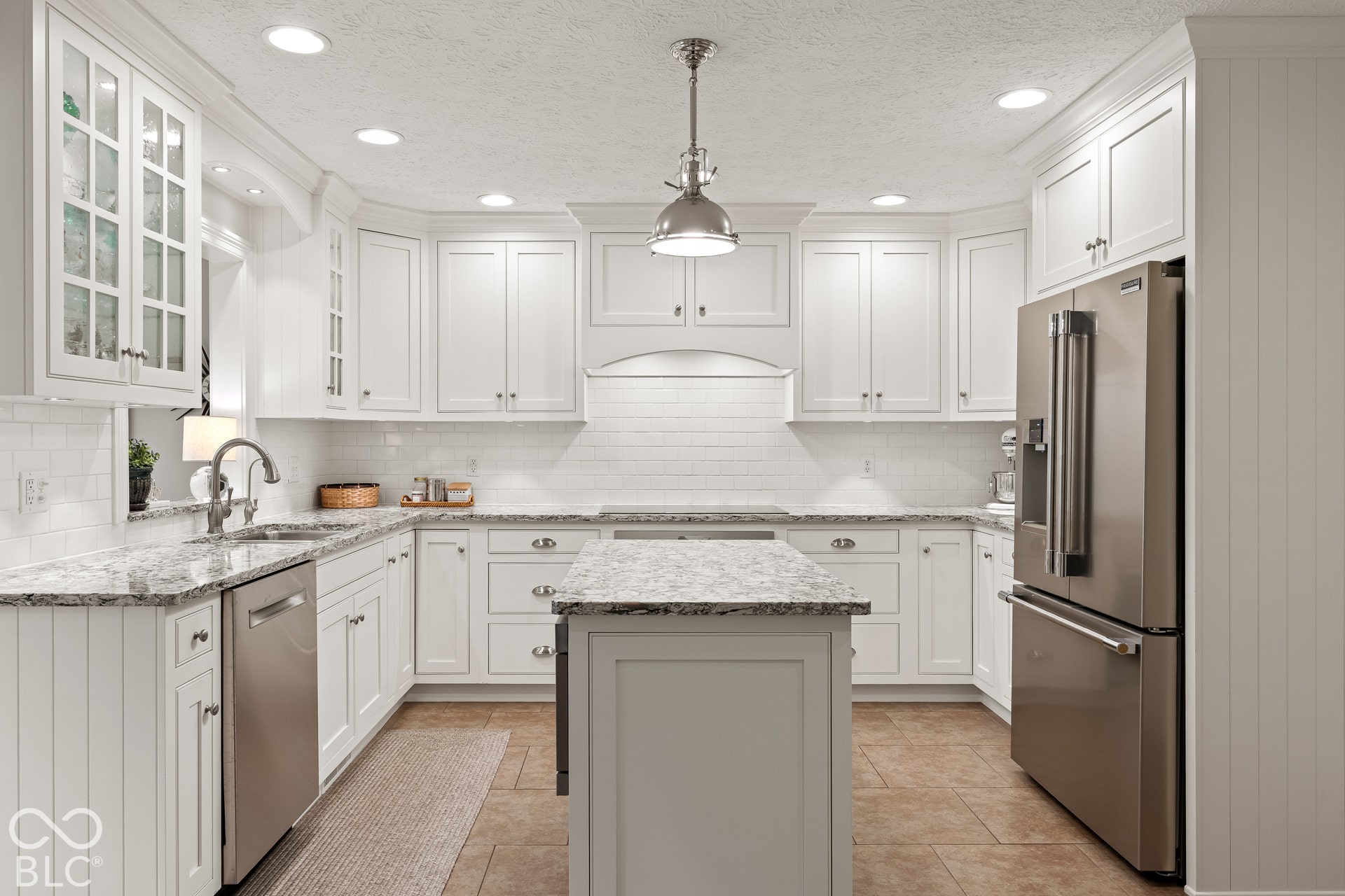 Kitchen featuring white shaker-style cabinetry, stone-surface countertops, subway tile backsplash, a central island, and stainless steel appliances