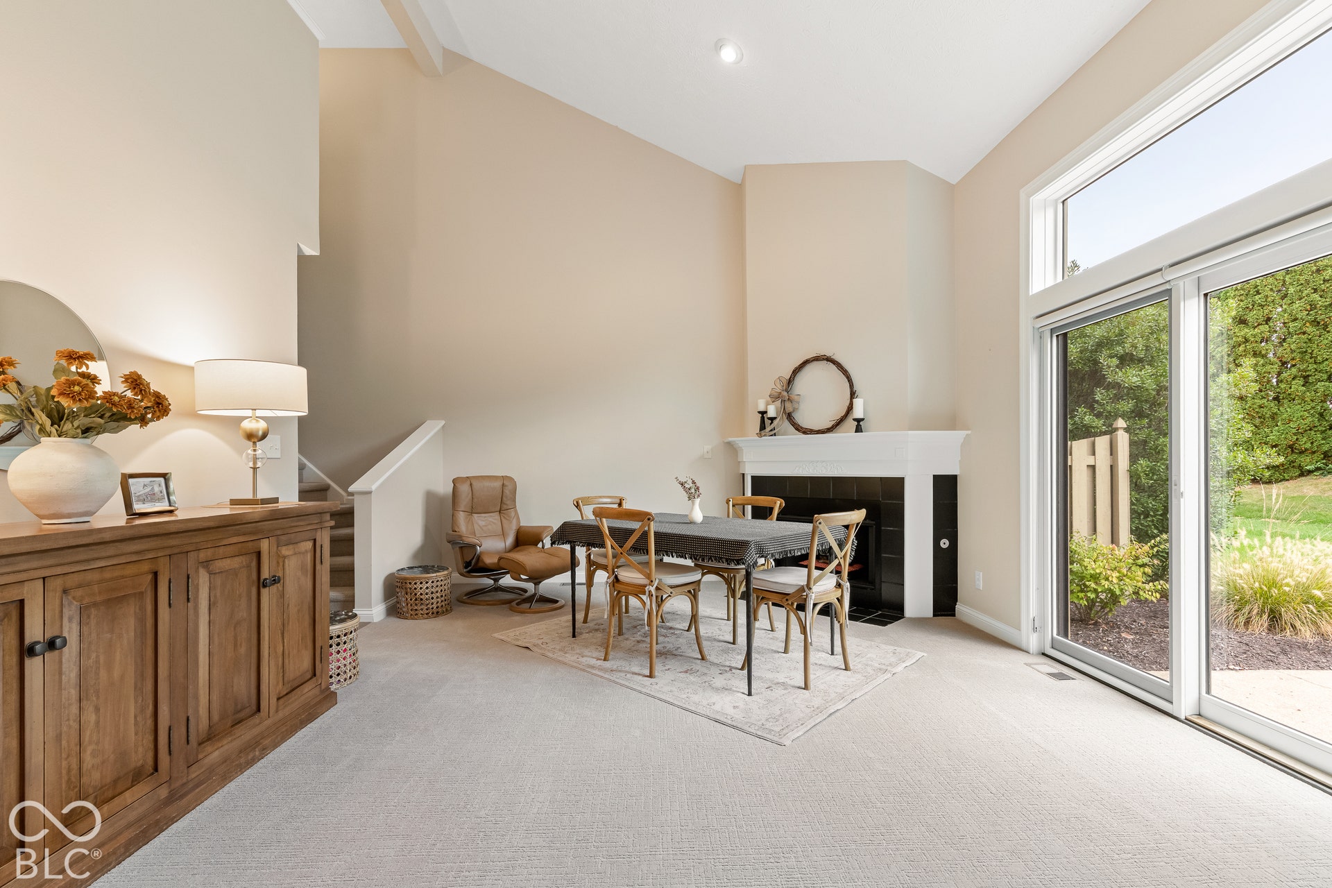 Vaulted ceilings, corner fireplace with a mantel, and sliding glass doors with a transom window