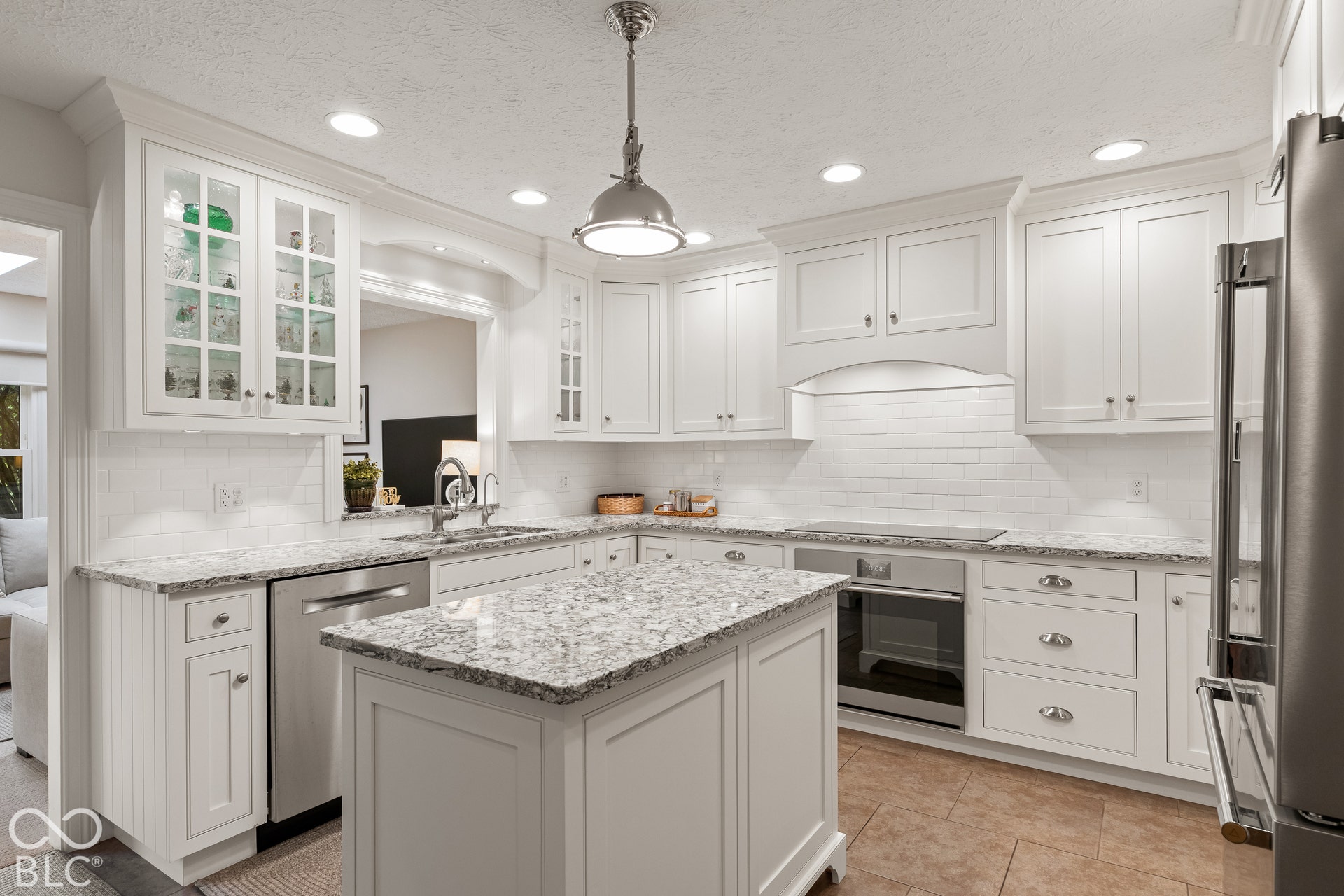 Kitchen featuring white cabinetry with glass-front uppers, stone-pattern countertops, a central island, stainless steel appliances, and tile backsplash
