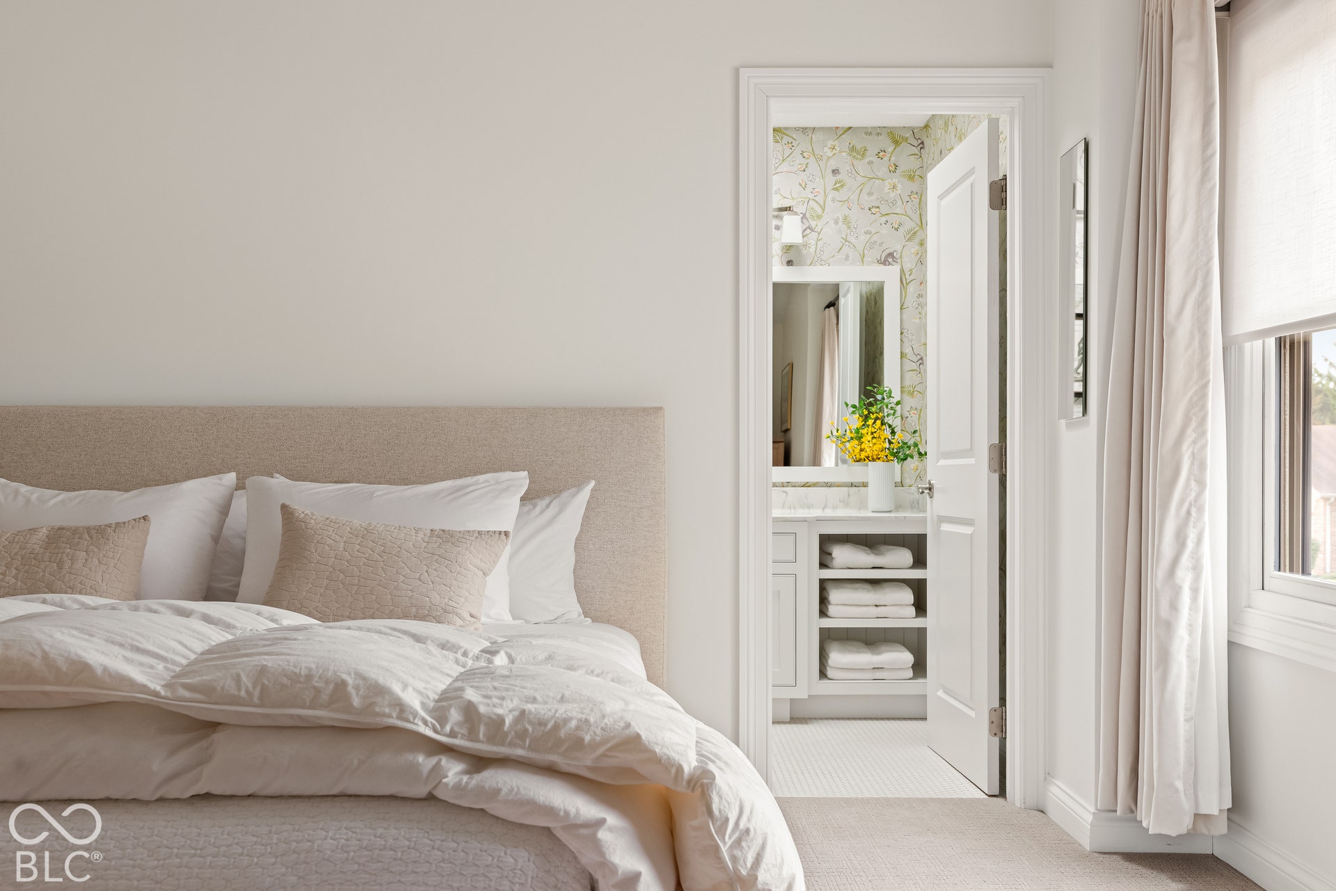 Neutral-toned carpeting, painted interior doors, and a bathroom featuring a stone-topped vanity with open shelving and patterned wall covering