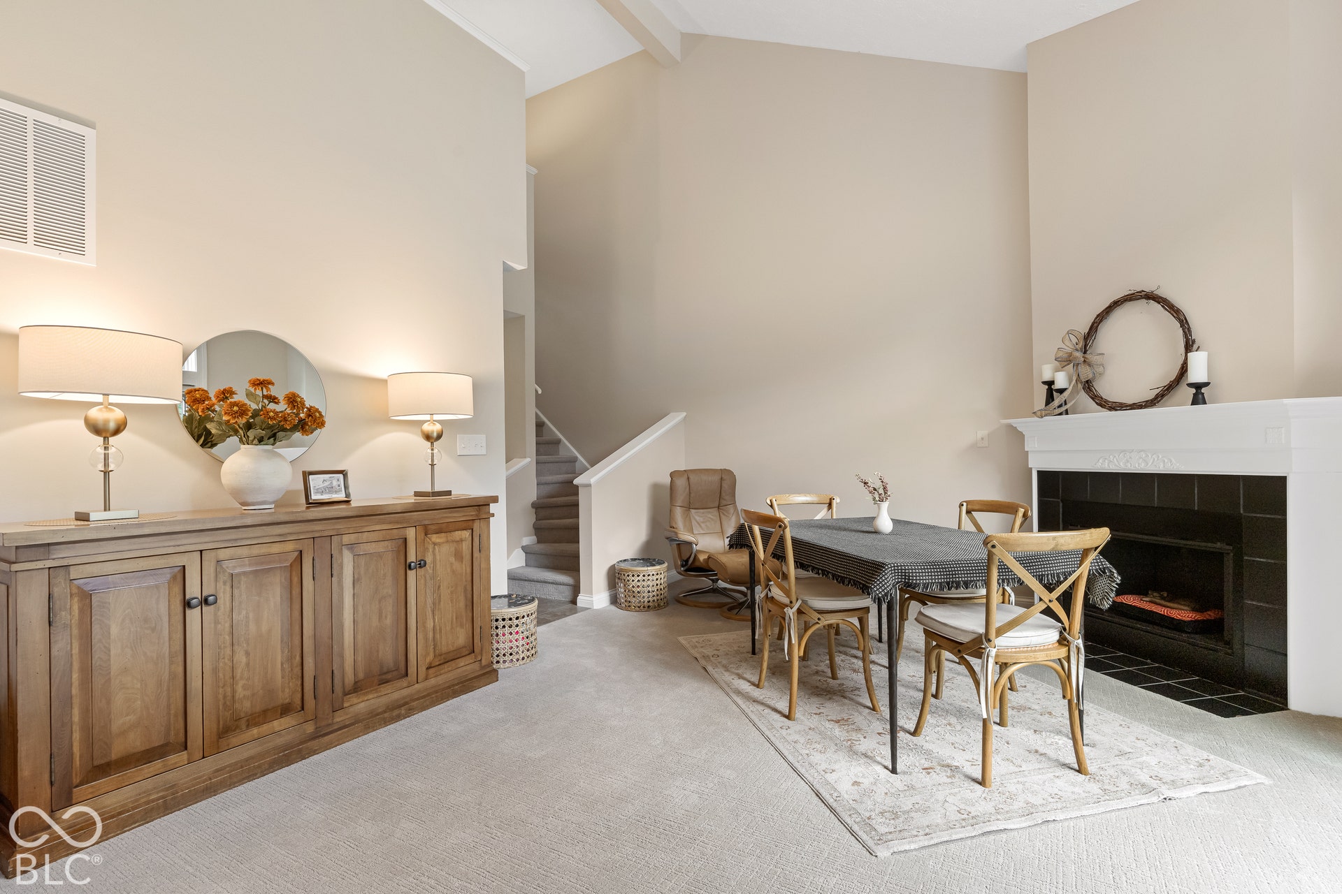Vaulted ceilings, fireplace with black tile surround, and neutral wall tones