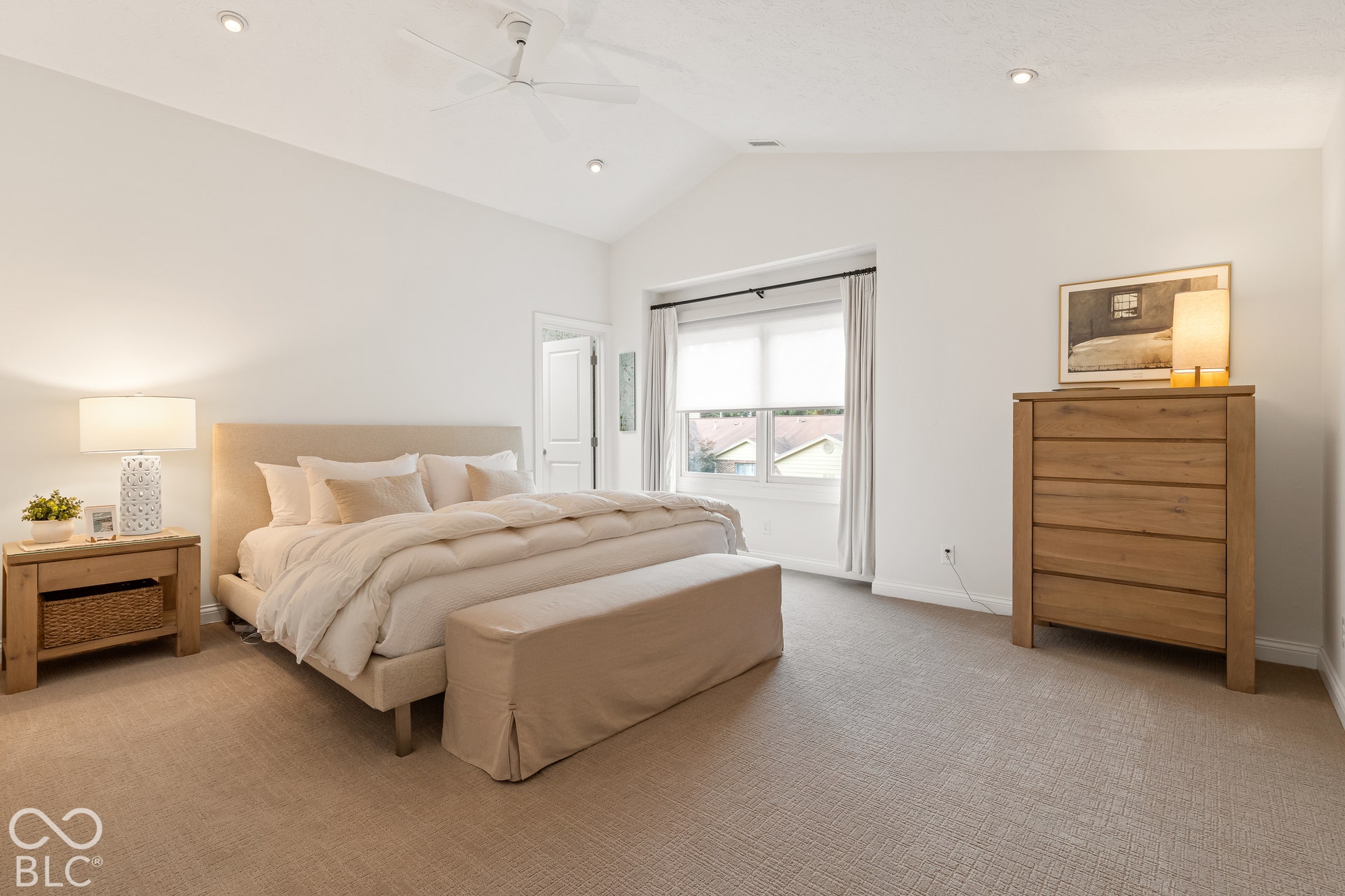 Vaulted ceilings featuring recessed lighting and a central ceiling fan, paired with neutral carpeting and a deep-set window featuring roller shades