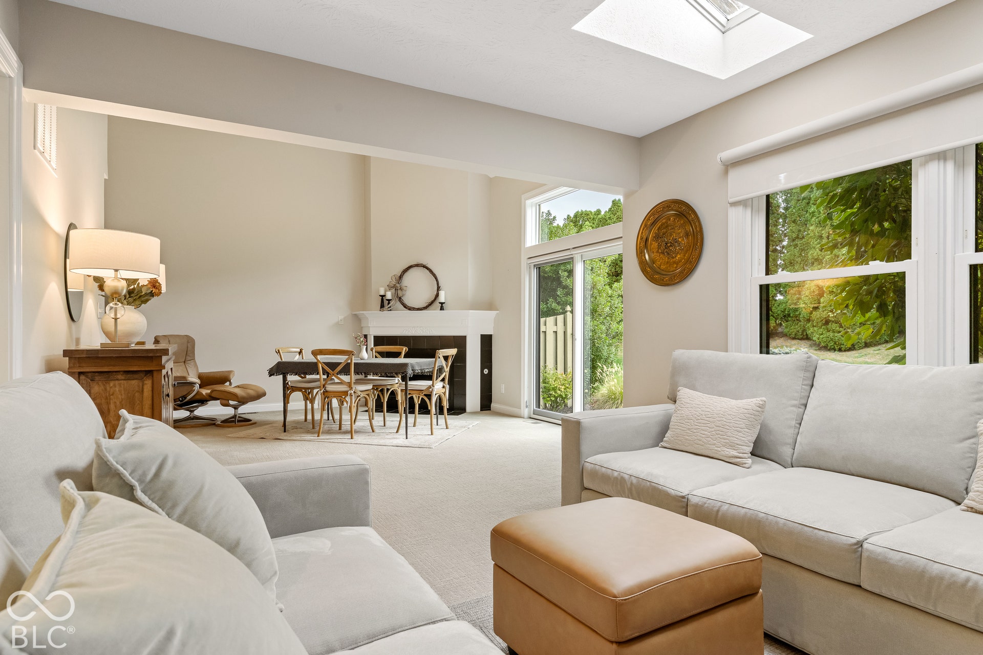 Open-concept interior featuring a corner fireplace with a mantel, a skylight, and large windows providing exterior exposure