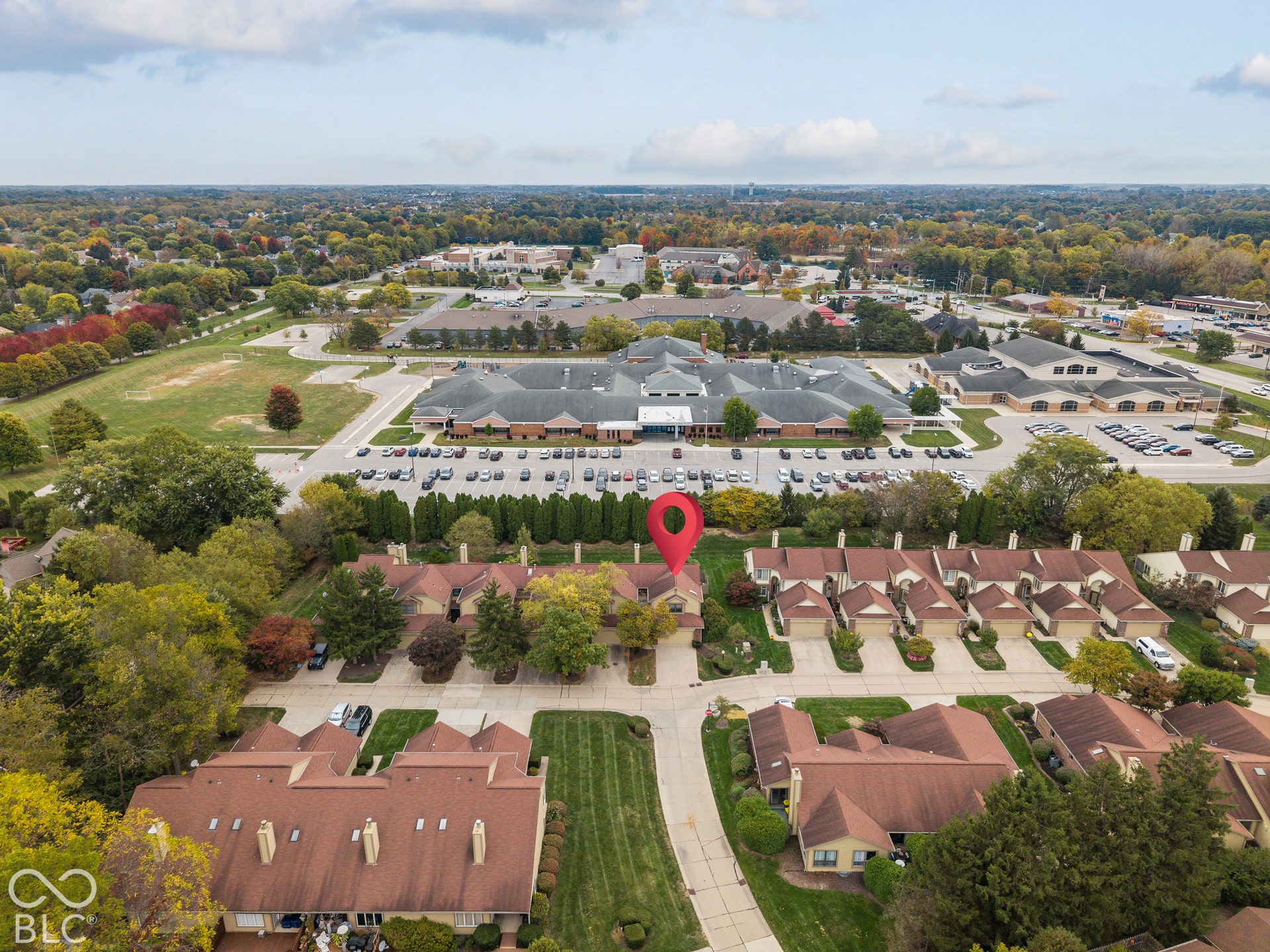 Aerial perspective of a multi-unit residential development featuring shingle roofing, brick facades, concrete driveways, and mature landscaping