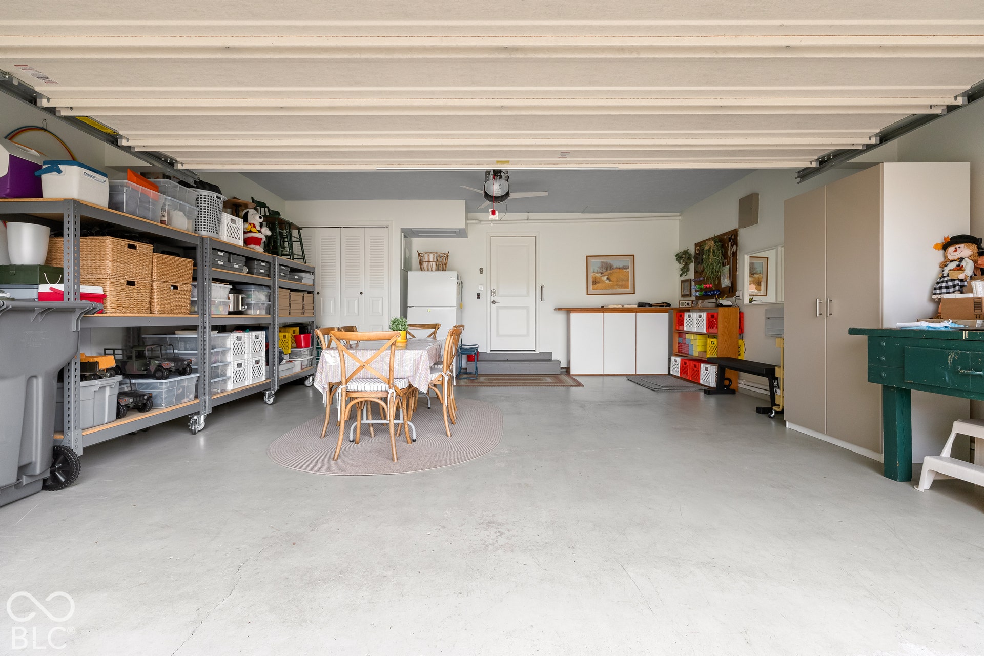 Attached garage featuring painted concrete flooring, ceiling-mounted lighting, and built-in storage cabinetry