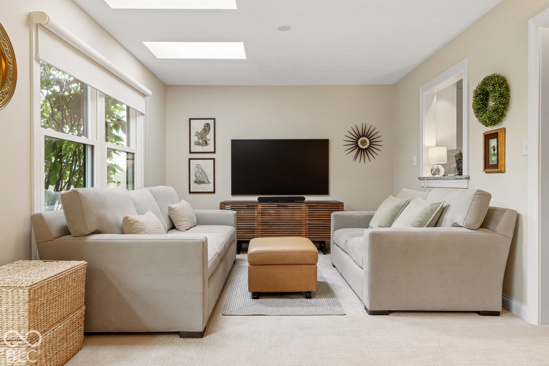 Living area featuring dual skylights, expansive windows, neutral wall finishes, and a pass-through opening