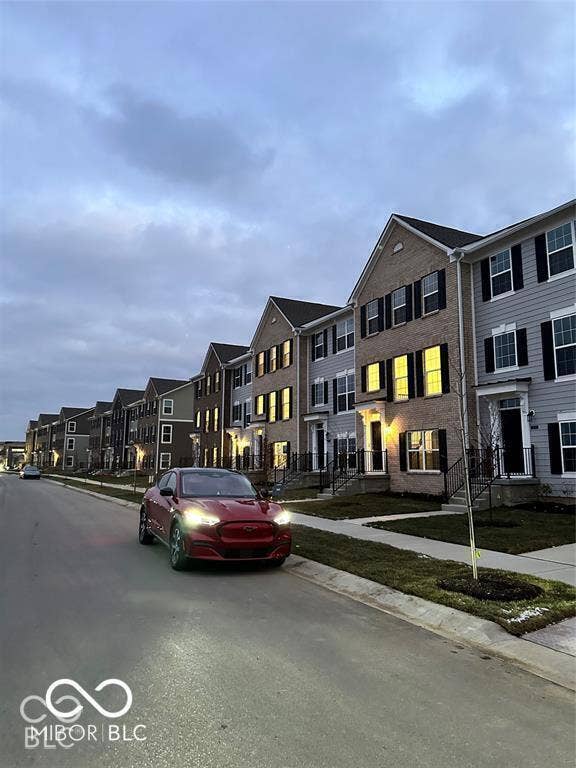 Multi-story residential exteriors featuring brick and horizontal lap siding, gable rooflines, decorative window shutters, and covered front entryways