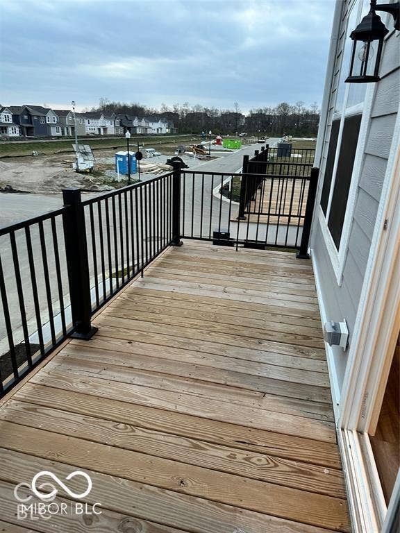 Elevated wooden deck featuring black metal railings and a wall-mounted exterior light fixture