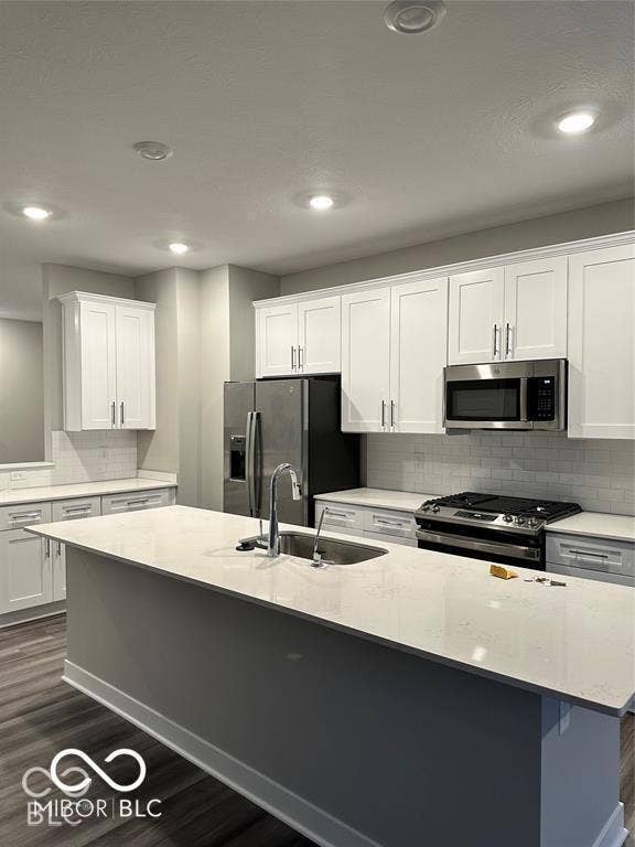 Kitchen featuring an expansive island with a quartz countertop, white shaker-style cabinetry, a white subway tile backsplash, stainless steel appliances, and recessed lighting
