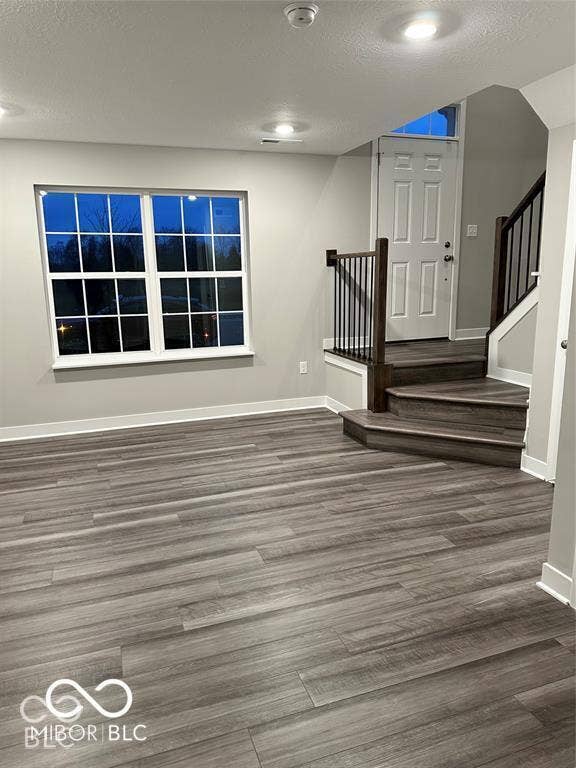 Interior space featuring wood-finish flooring, recessed lighting, a multi-pane window, and a staircase with metal balusters and wood-finish handrail